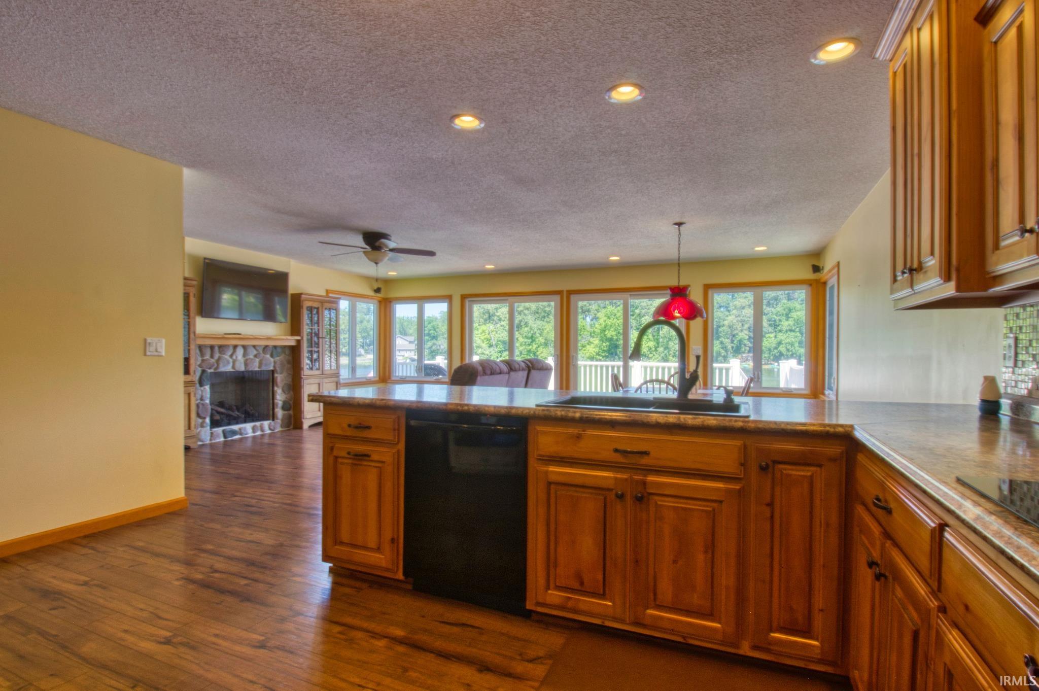 Kitchen island with integrated sink and dishwasher, featuring wood cabinetry and a stone-finish countertop