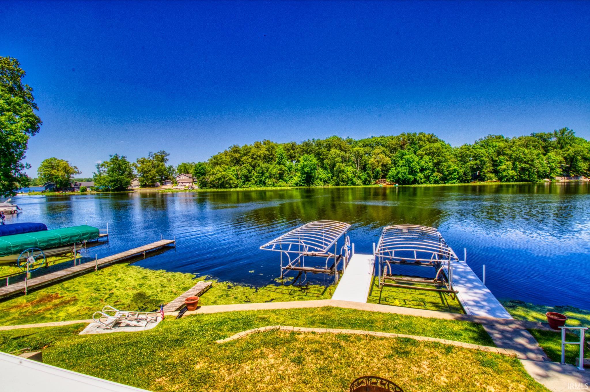 Waterfront property featuring multiple docks, two boat lifts with canopies, and a grassy shoreline