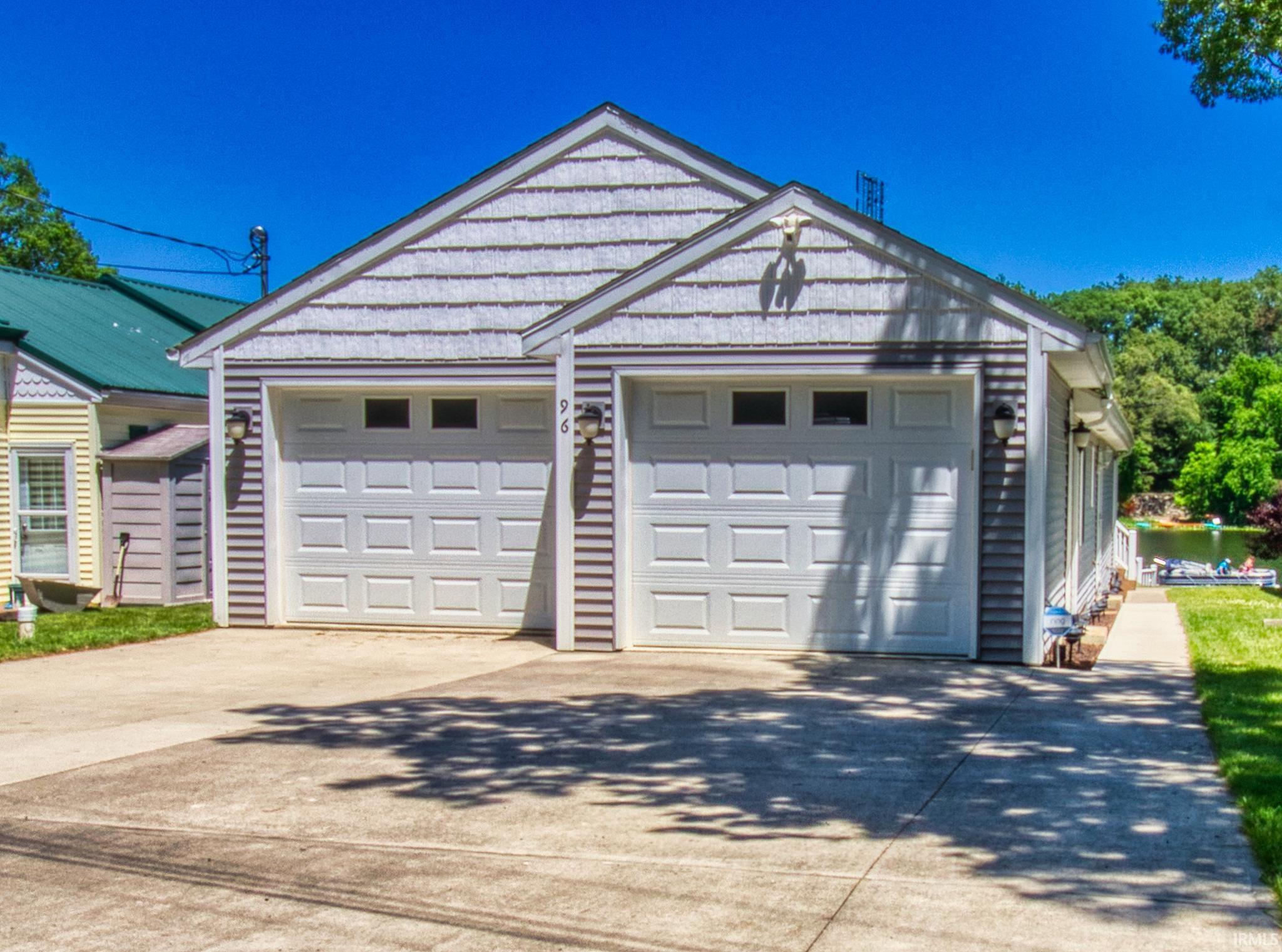 Two-car garage with panel-style doors and upper windows, featuring shingle and horizontal siding, exterior lighting fixtures, and a concrete driveway