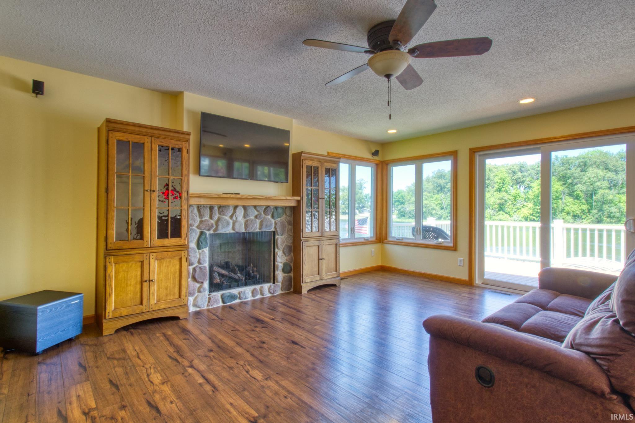 Living area featuring wood-finish flooring and a stone-faced fireplace with a wood mantel