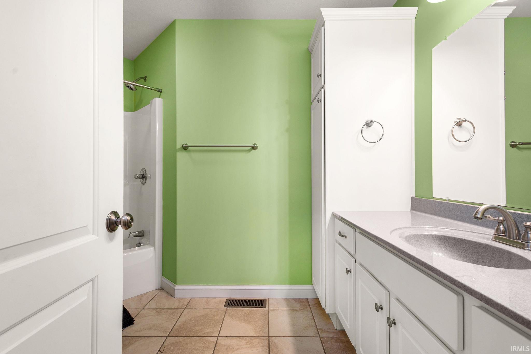 Bathroom featuring a white vanity with an integrated sink and brushed nickel faucet, a tall built-in storage cabinet, and a shower-over-tub combination with a white surround