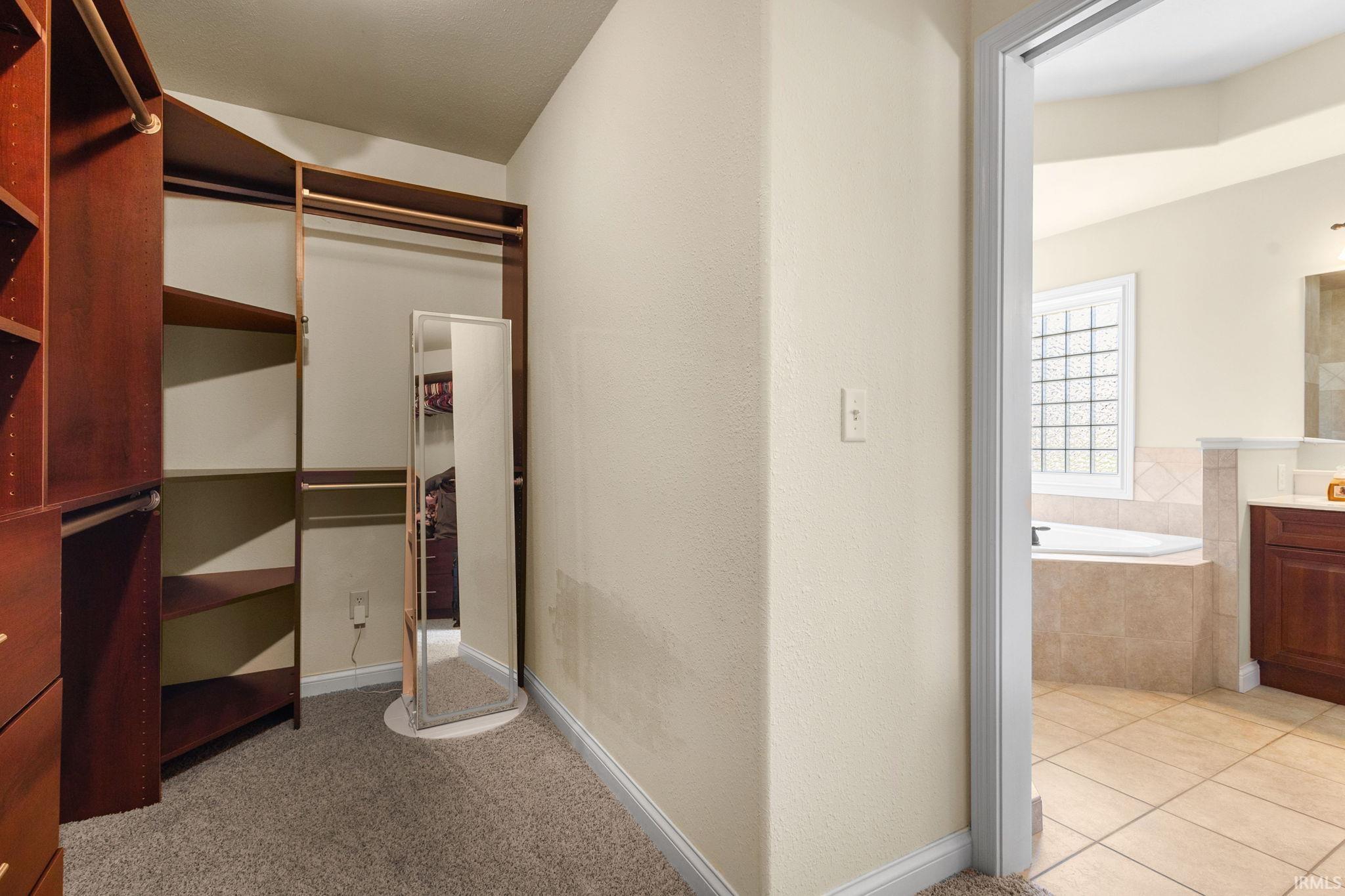 Walk-in closet featuring extensive built-in shelving, multiple hanging rods, and built-in drawers