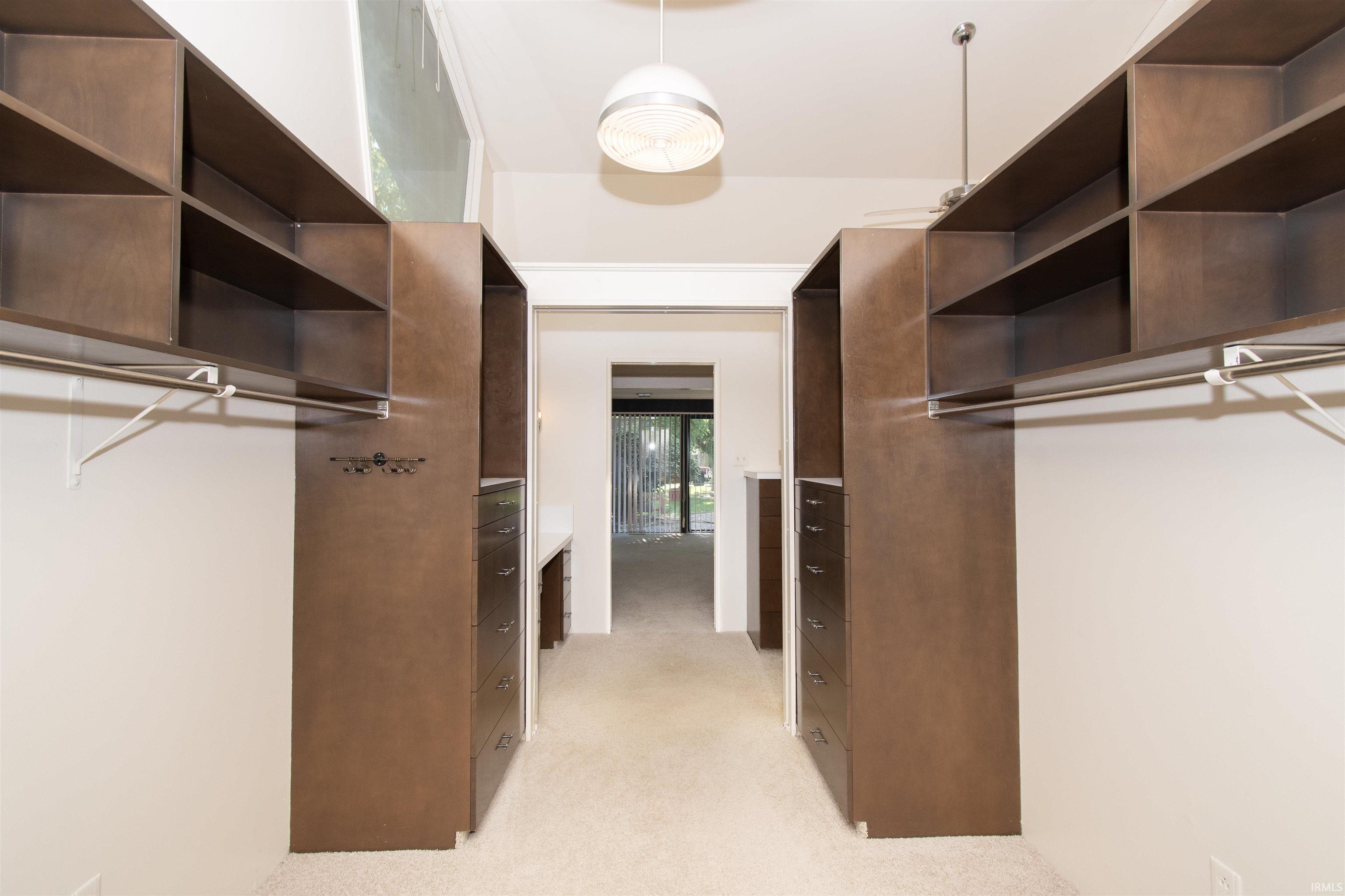 Custom closet system featuring wood-finish cabinetry, integrated shelving, hanging rods, and built-in drawers