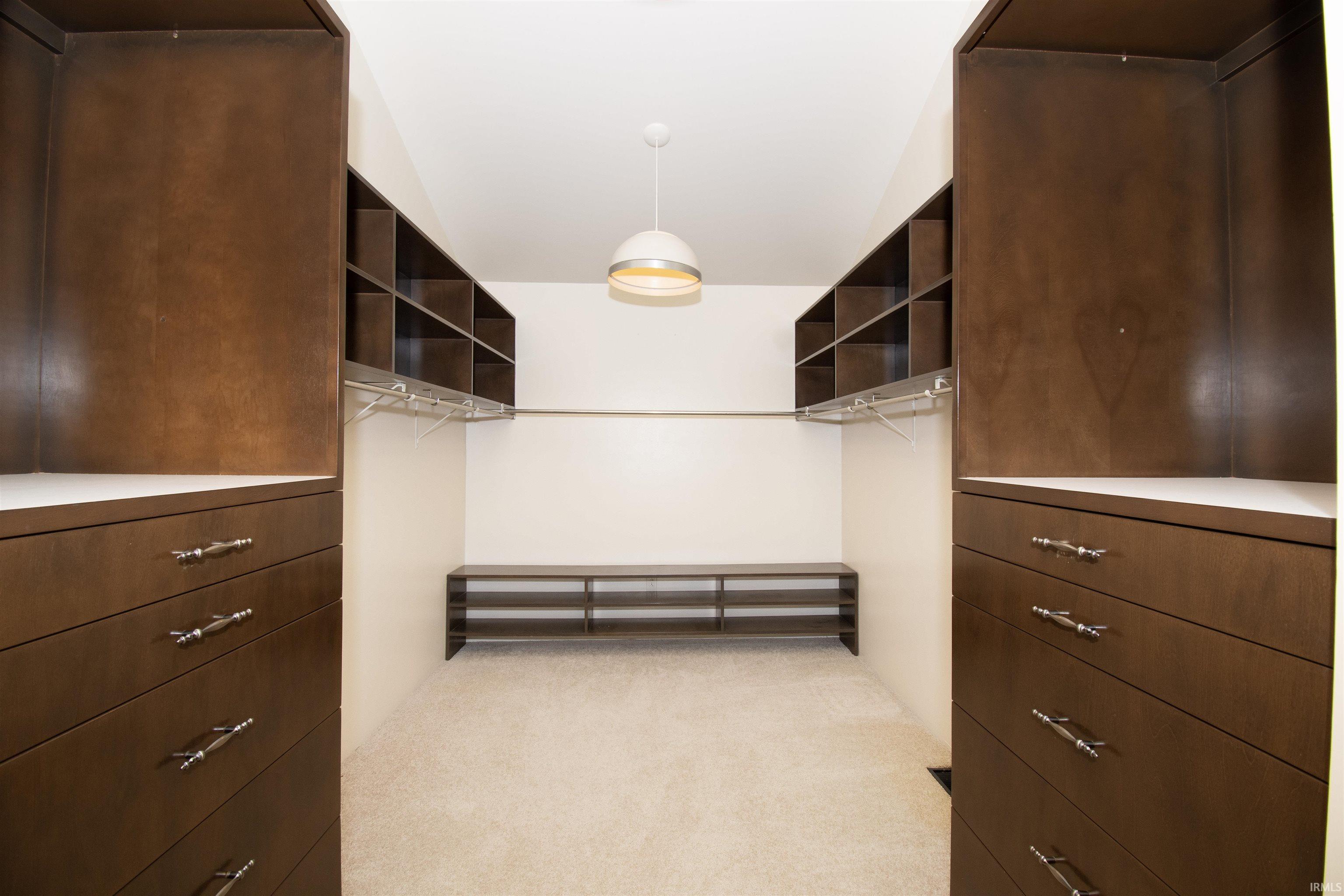 Custom closet system featuring rich wood-finish cabinetry, built-in shelving, and drawers with brushed nickel hardware