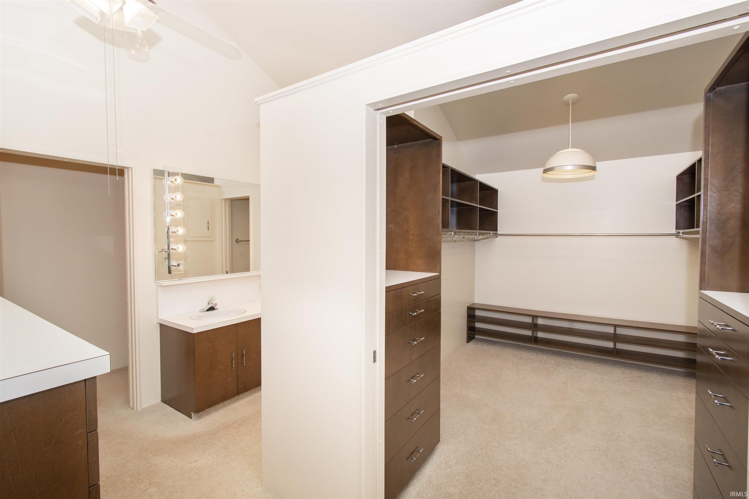 Spacious walk-in closet with custom built-ins, ample shelving, integrated drawers, and a central hanging rod