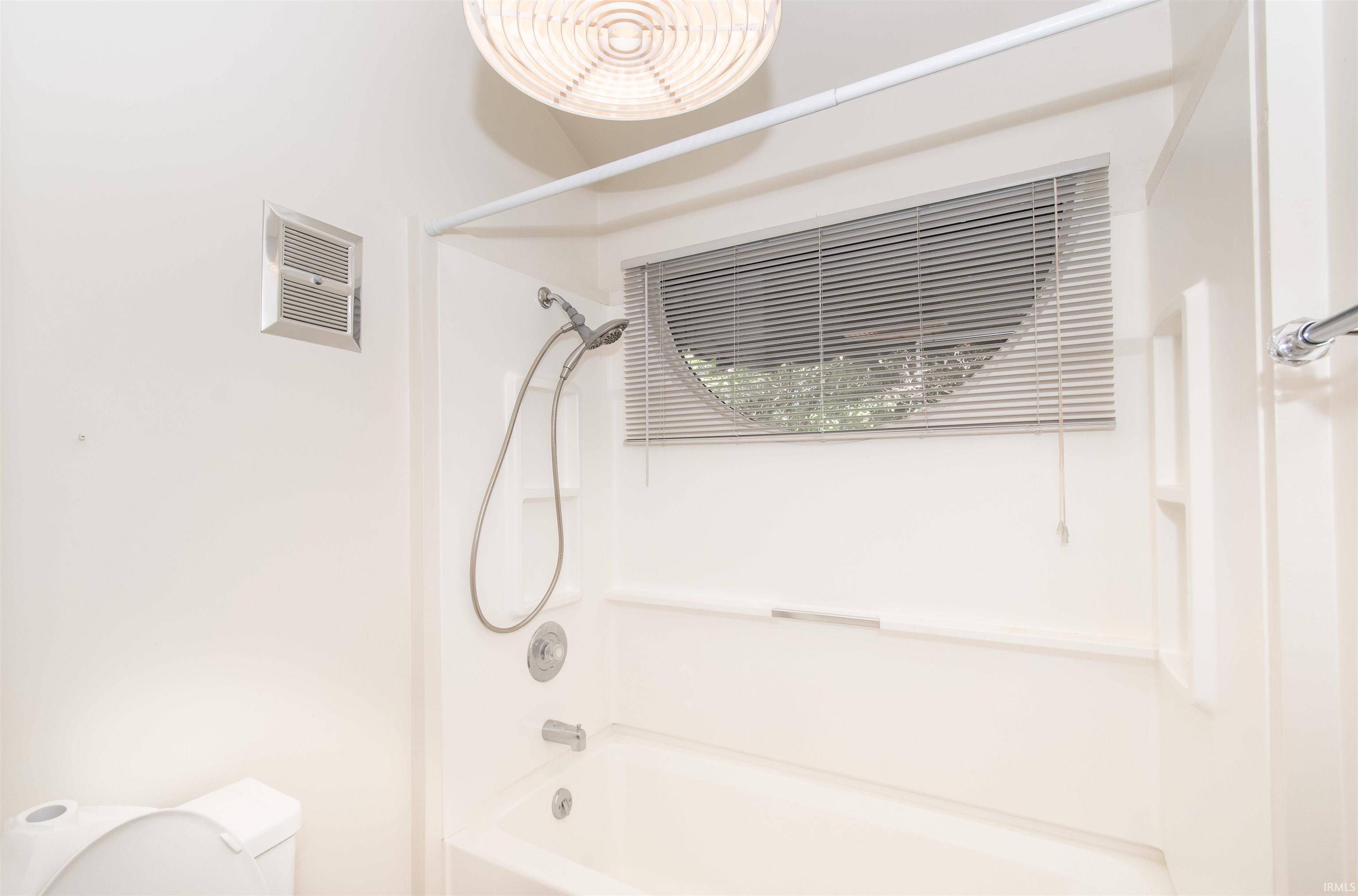 Bathroom featuring a white bathtub and shower combination with a flexible showerhead