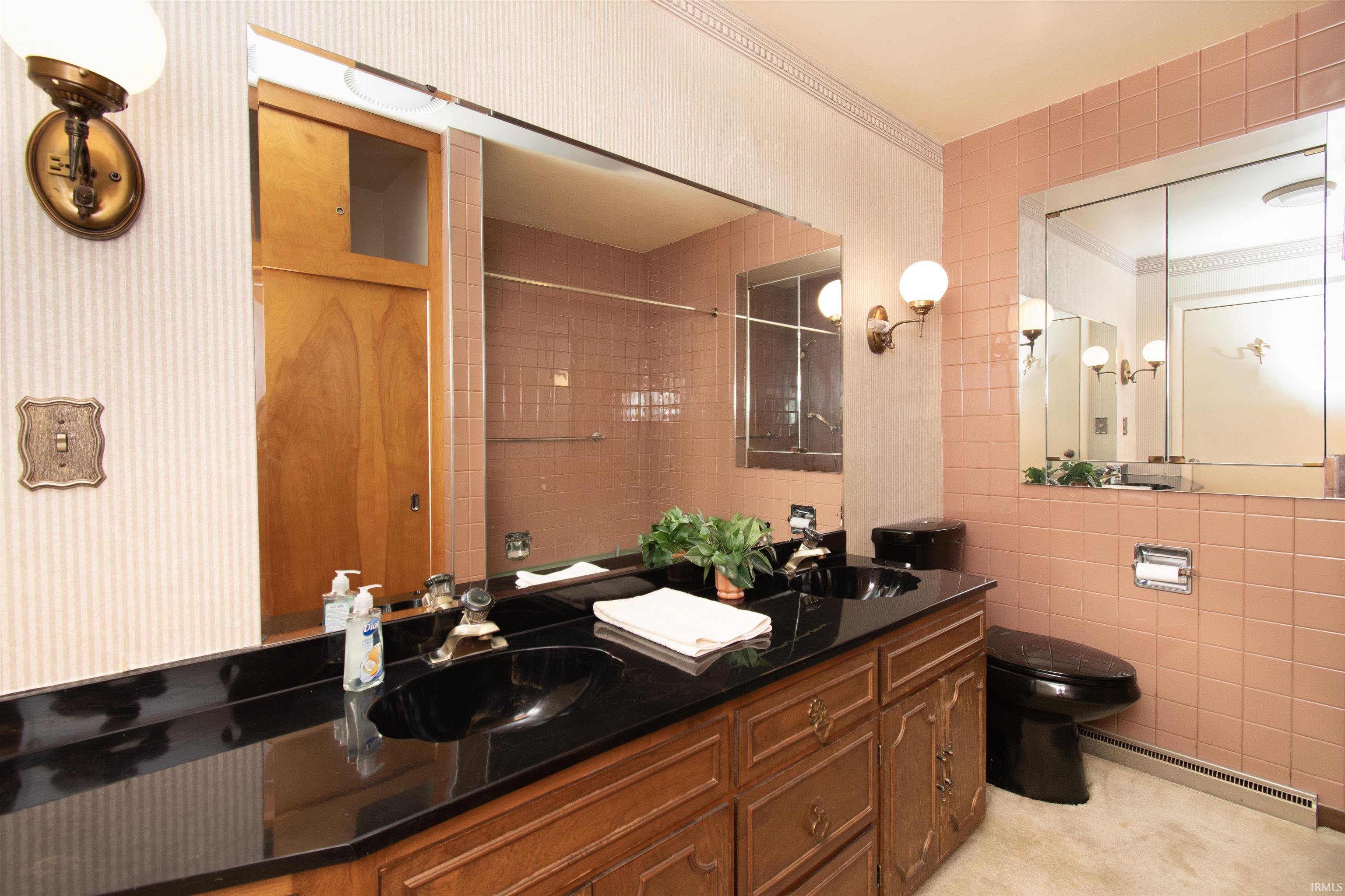 Bathroom featuring a dual-sink vanity with a dark countertop and wood cabinetry