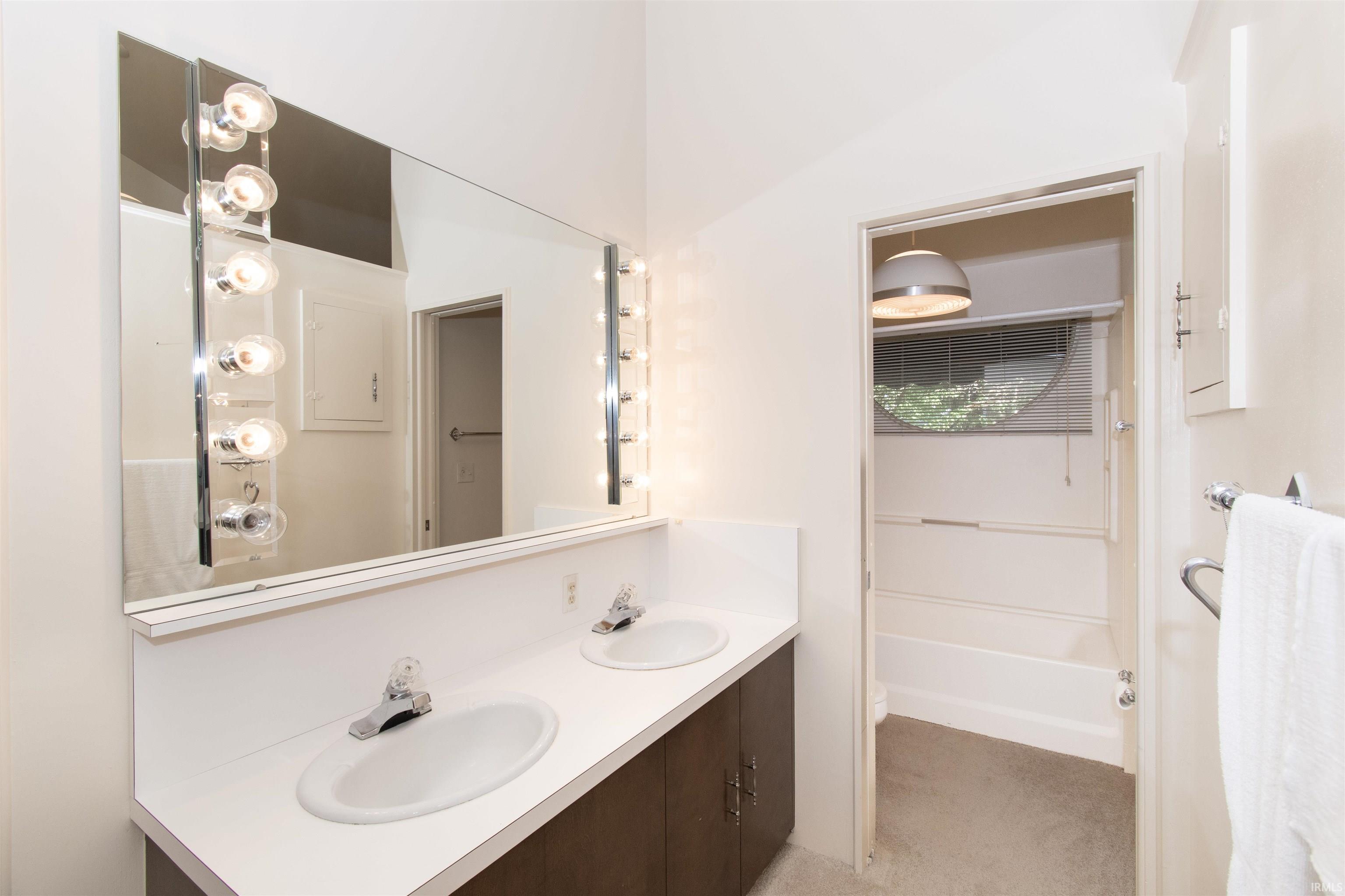 Dual vanity with white countertops, integrated sinks, and dark wood-finish cabinetry