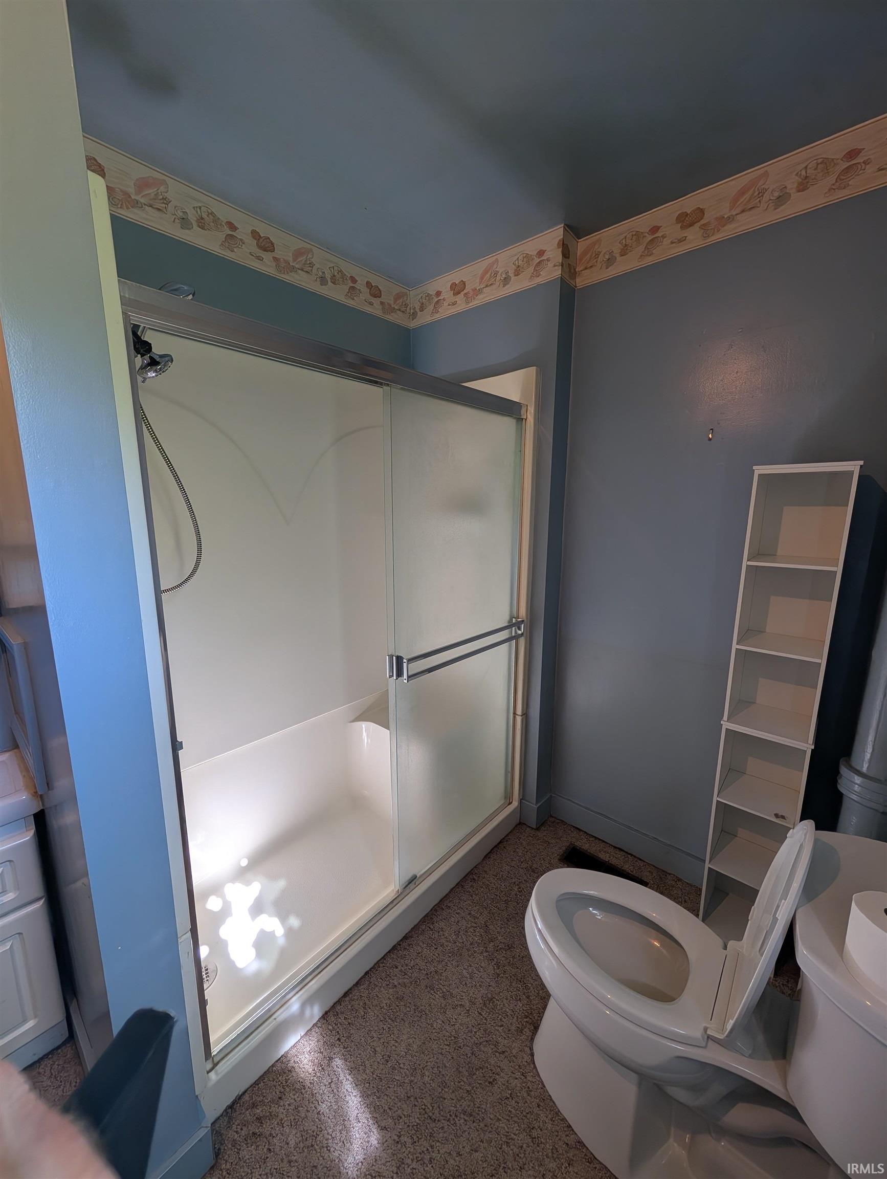 Shower enclosure with frosted sliding glass doors, integrated seating, and a handheld shower fixture