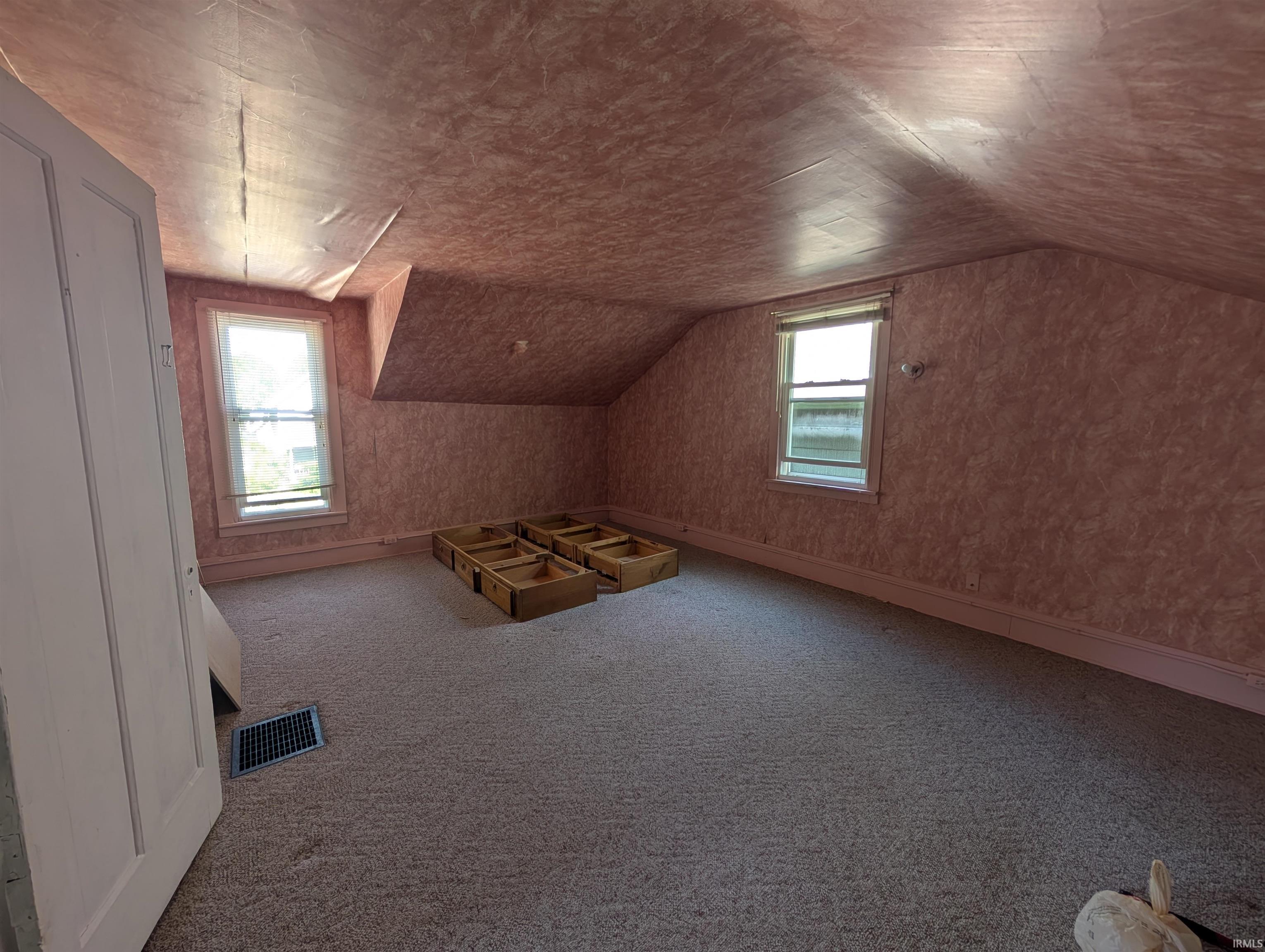 Carpeted room featuring a sloped ceiling and two windows