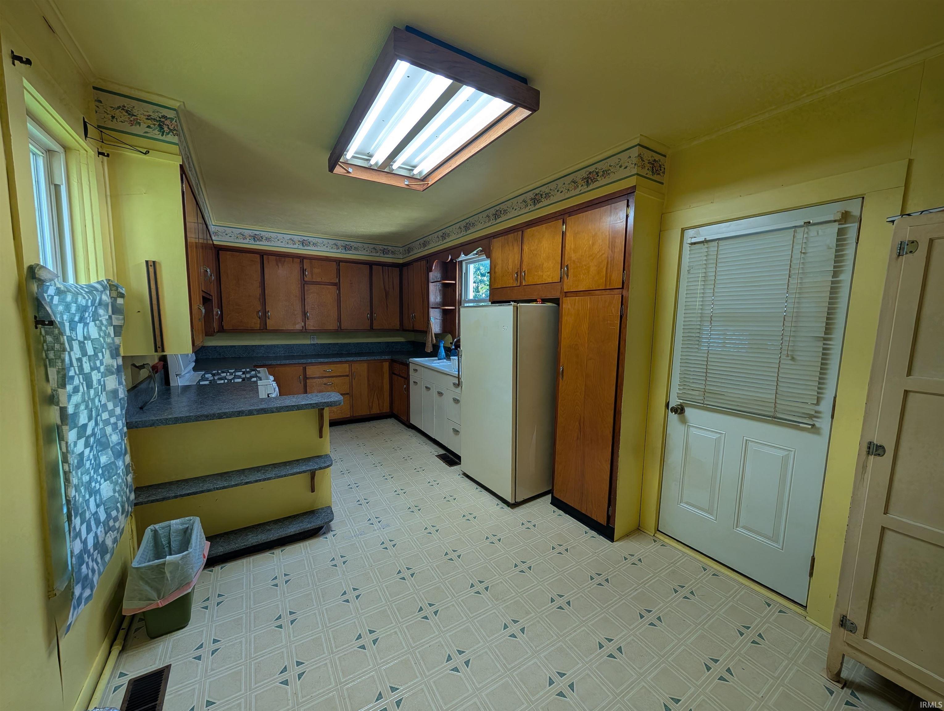Kitchen featuring wood cabinetry, laminate countertops, and patterned flooring