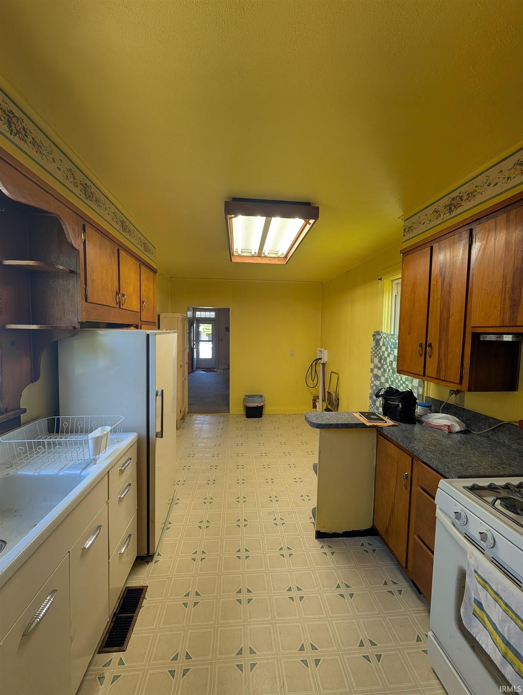 Spacious kitchen featuring a patterned flooring, wood cabinetry, built-in sink, and a gas range