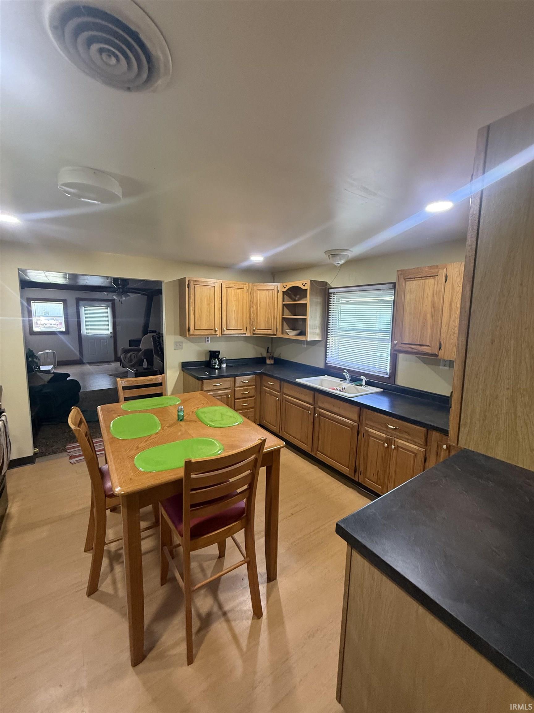 Kitchen featuring wood-finish flooring, recessed lighting, wood cabinetry, dark countertops, and a double basin sink