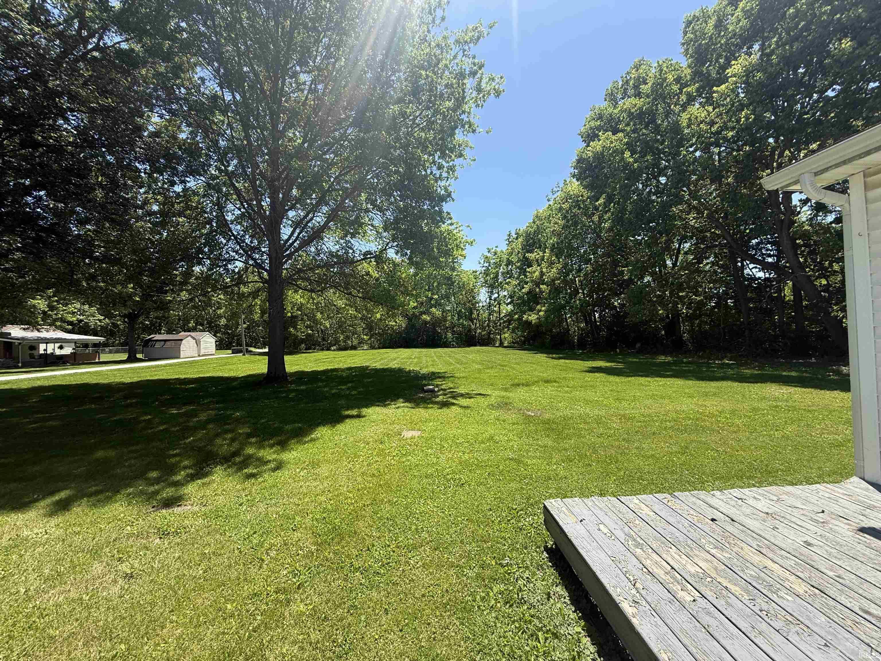 Expansive grass lawn with mature trees and a wood deck