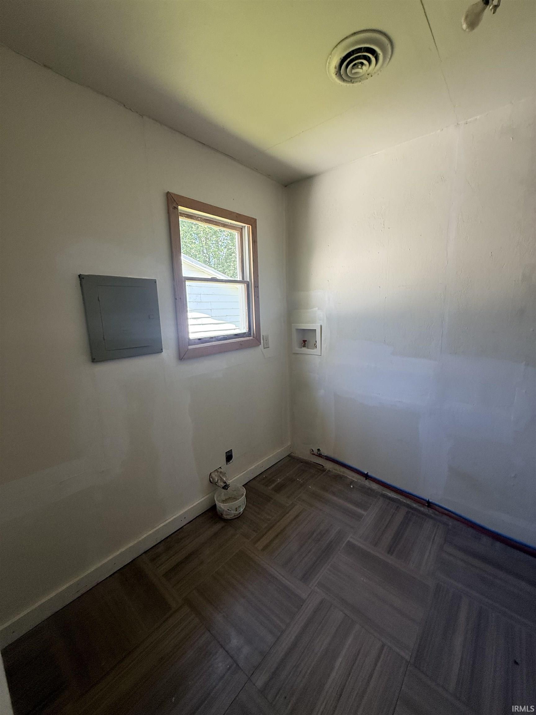 Utility room with wood-finish tile flooring, a window with wood trim, and visible plumbing connections