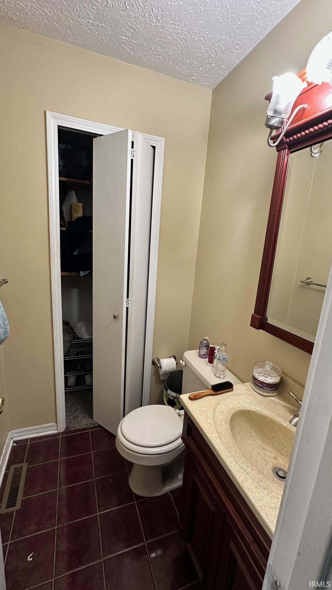 Bathroom featuring a dark wood-finish vanity with an integrated sink, a matching framed mirror, and a white toilet