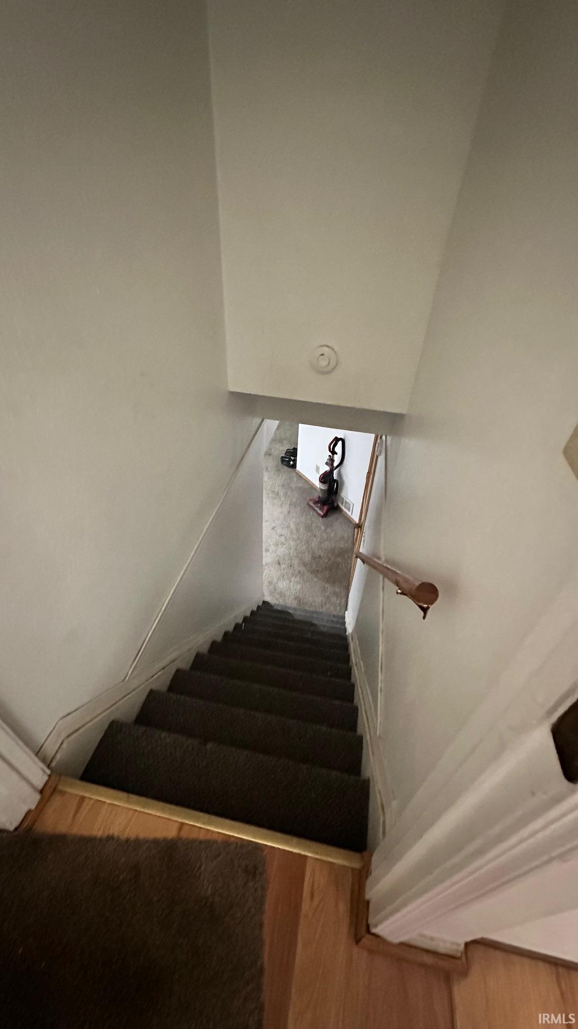 Stairway featuring carpeted treads, a wood handrail, and light wood-finish flooring at the landing