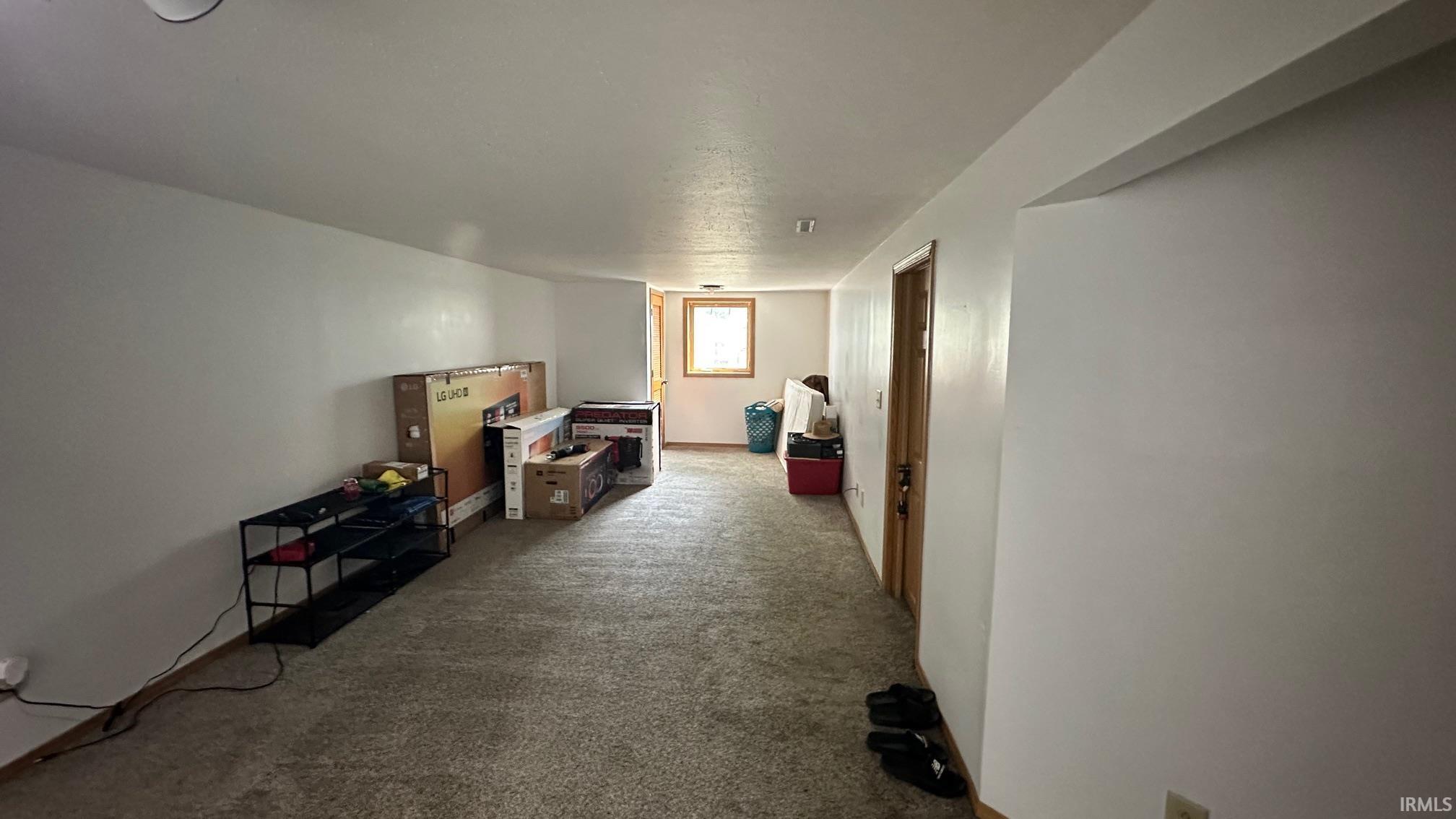 Spacious room featuring neutral carpeting, white painted walls, and a recessed ceiling light fixture