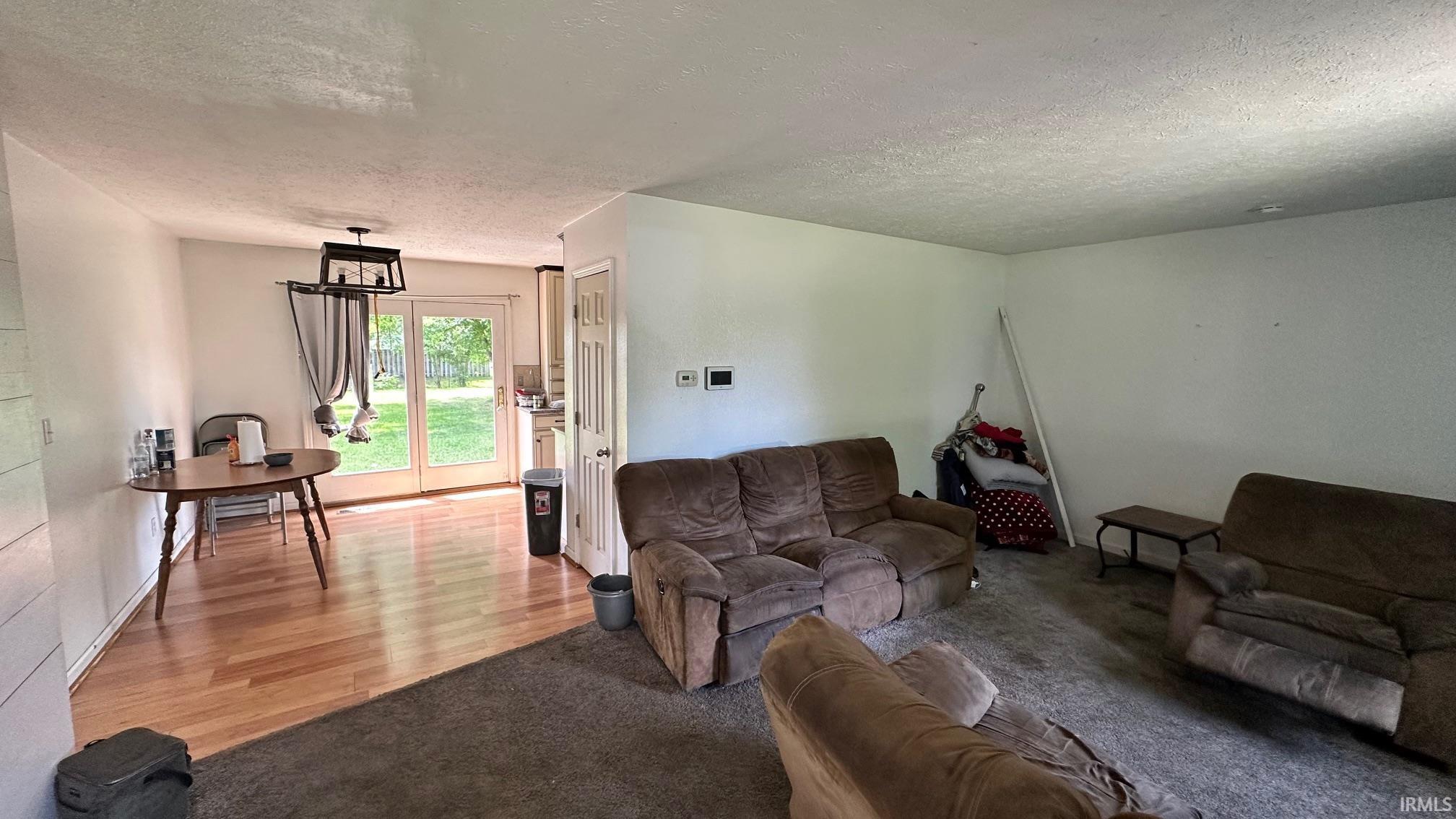Combined living and dining space featuring wood-finish flooring in the dining area and carpeting in the living area