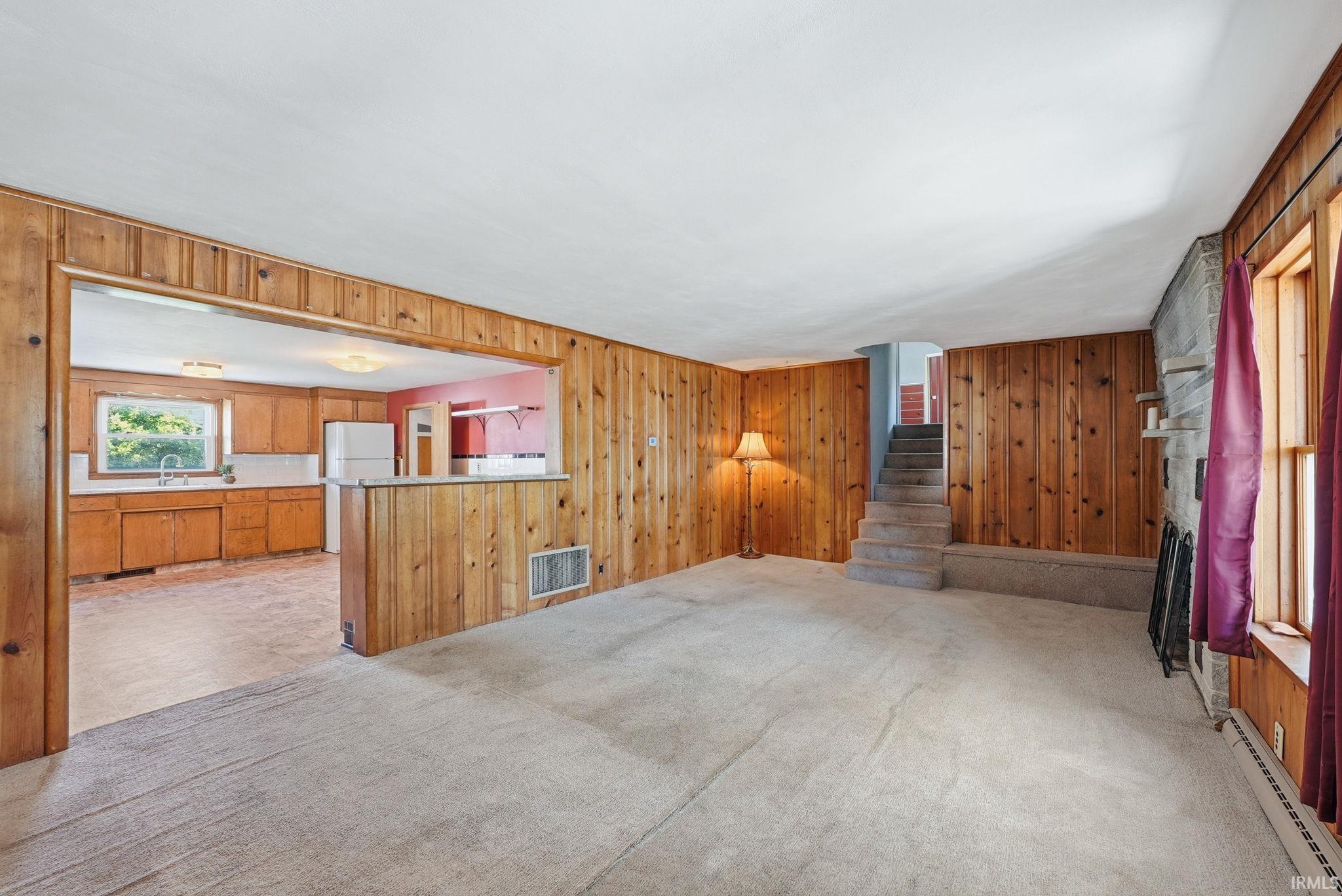 Expansive carpeted living area featuring wood-paneled walls and a stone accent wall