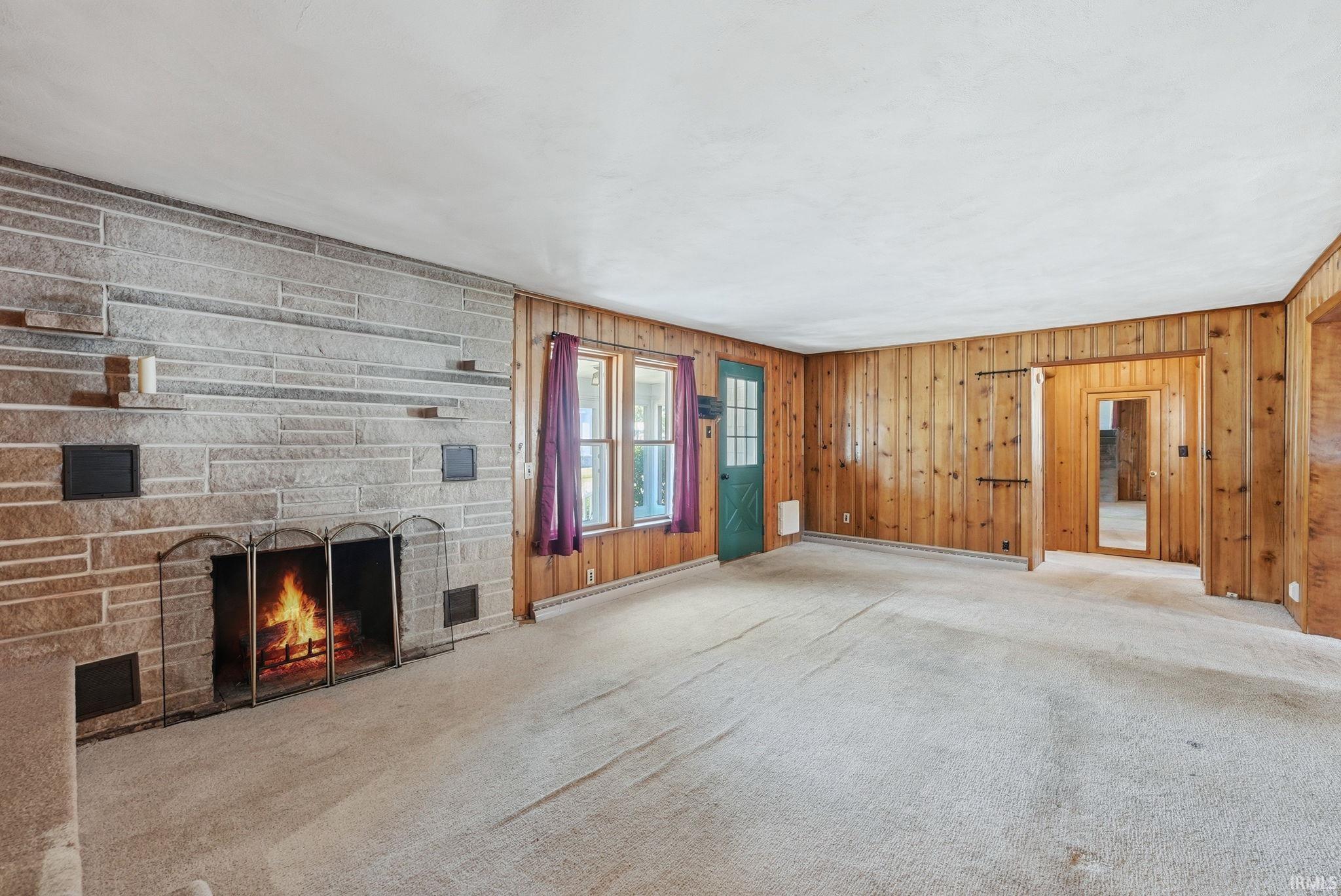 Spacious room featuring a stone-clad fireplace and wood paneling