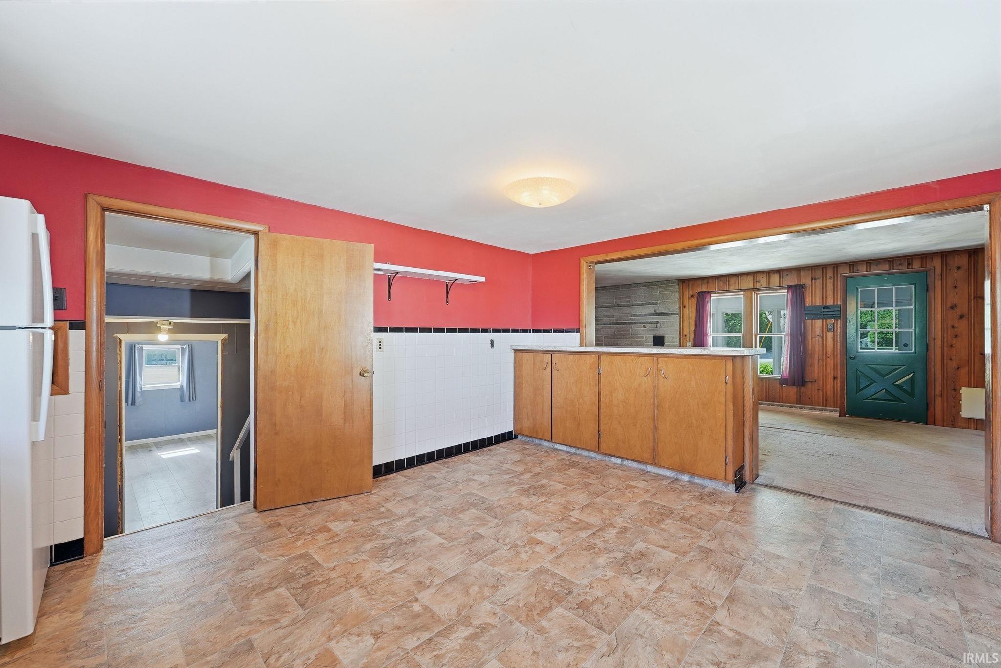 Kitchen with wood-finish flooring, built-in cabinetry, and a bright red accent wall