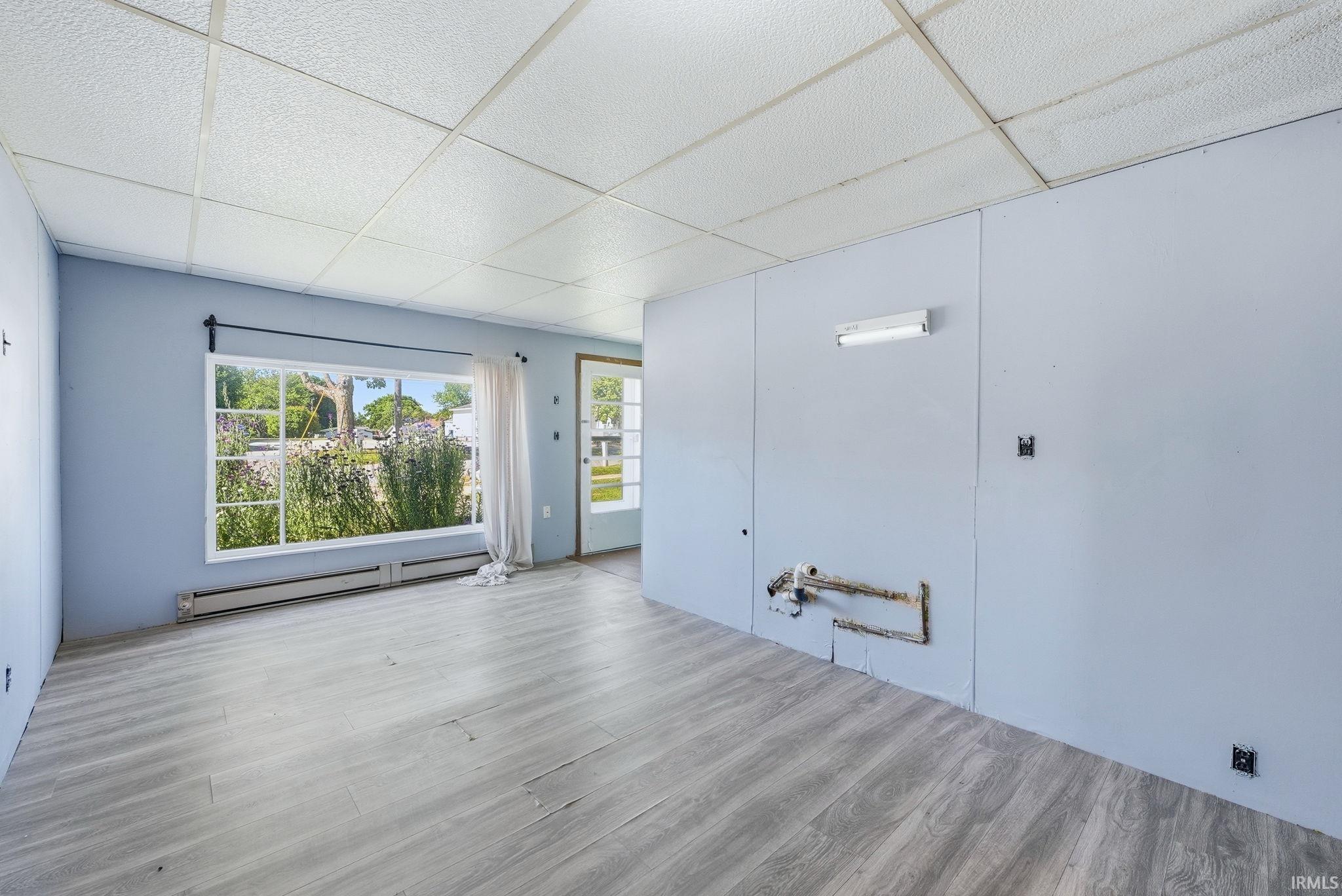 Expansive interior space featuring wood-finish flooring, a large picture window, and paneled walls