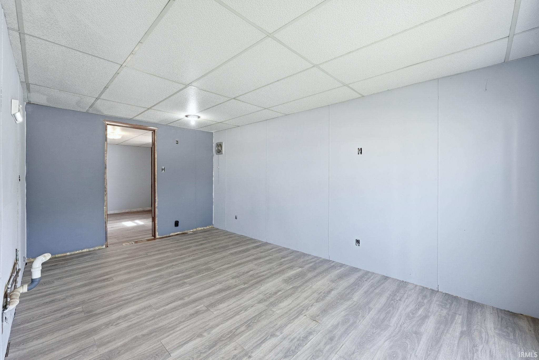 Spacious room featuring wood-finish flooring and a drop ceiling