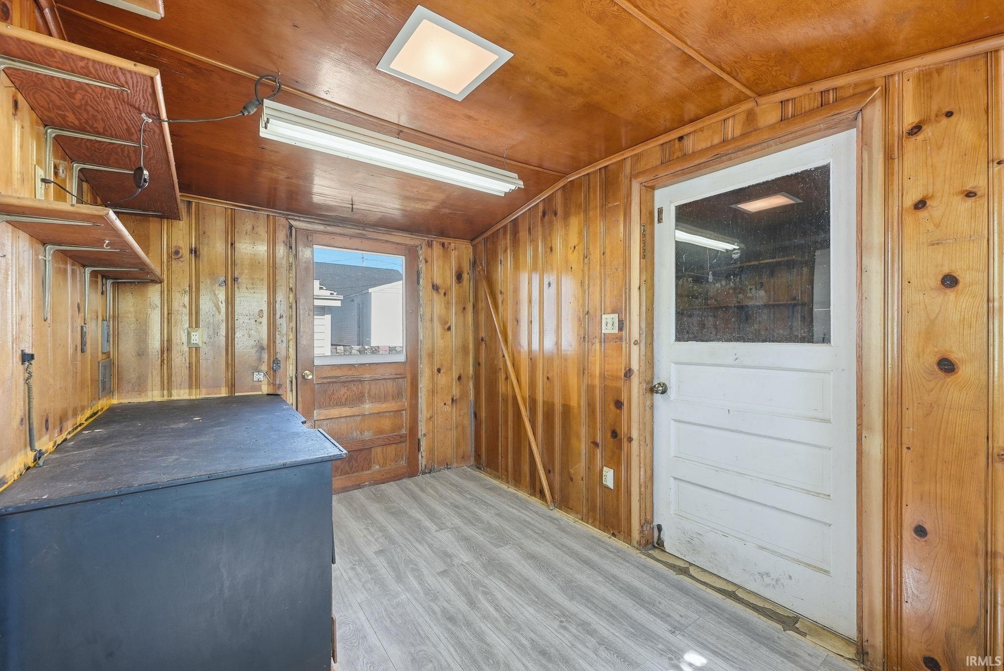 Room featuring wood-paneled walls and ceiling, light wood-finish flooring, and recessed ceiling lighting
