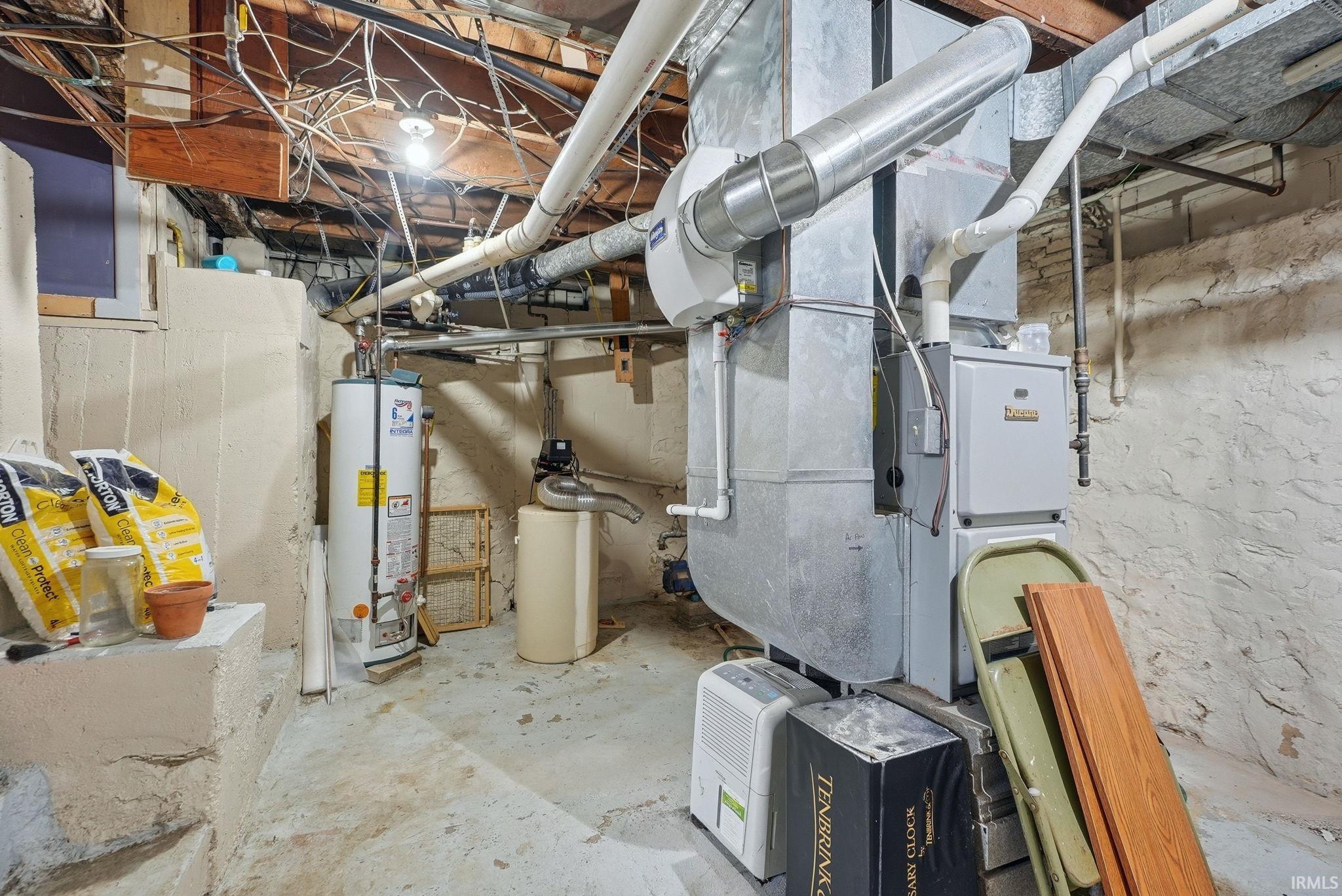 Basement utility area featuring a furnace, hot water heater, and exposed ductwork