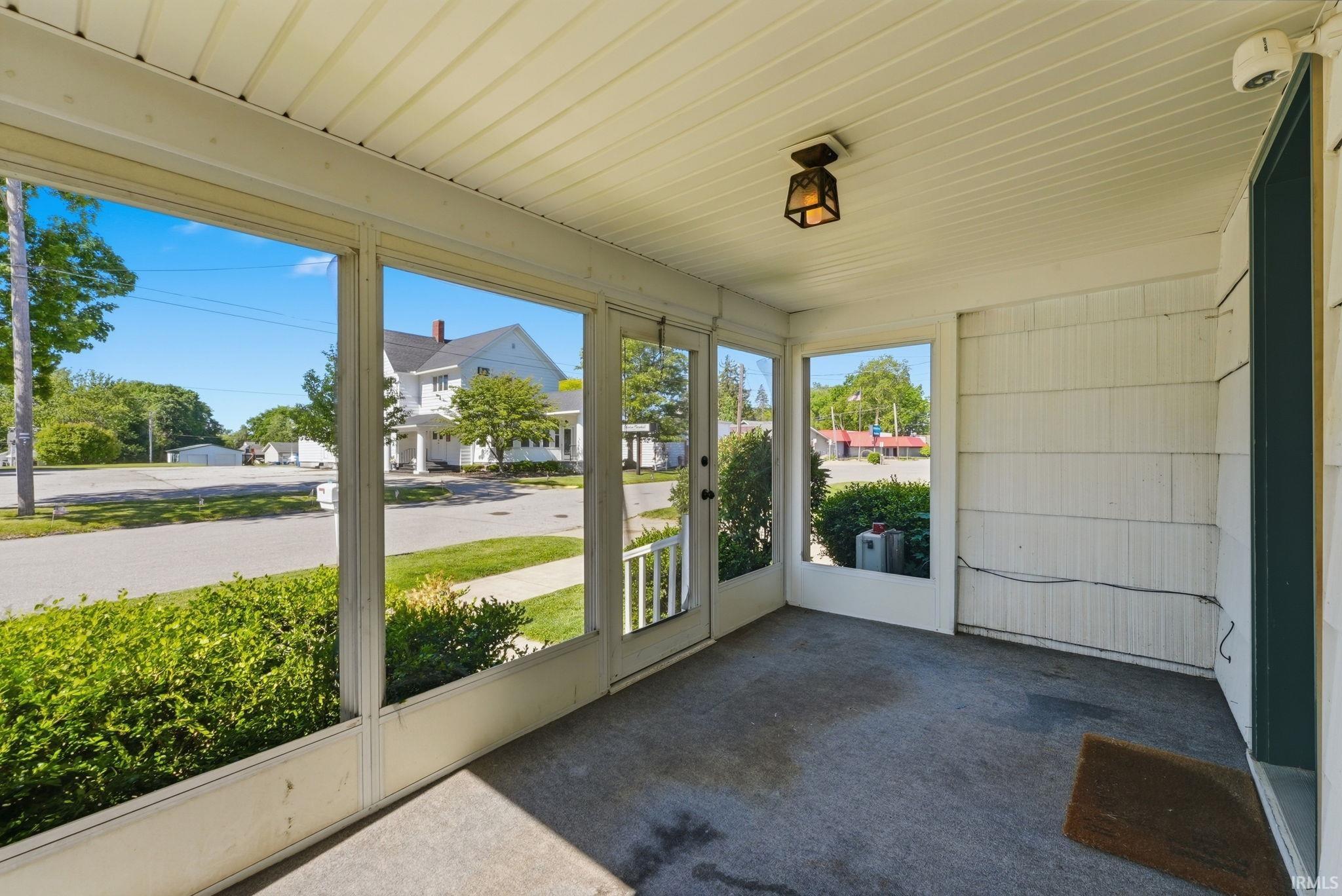 Screened porch with concrete flooring and a ceiling-mounted light fixture