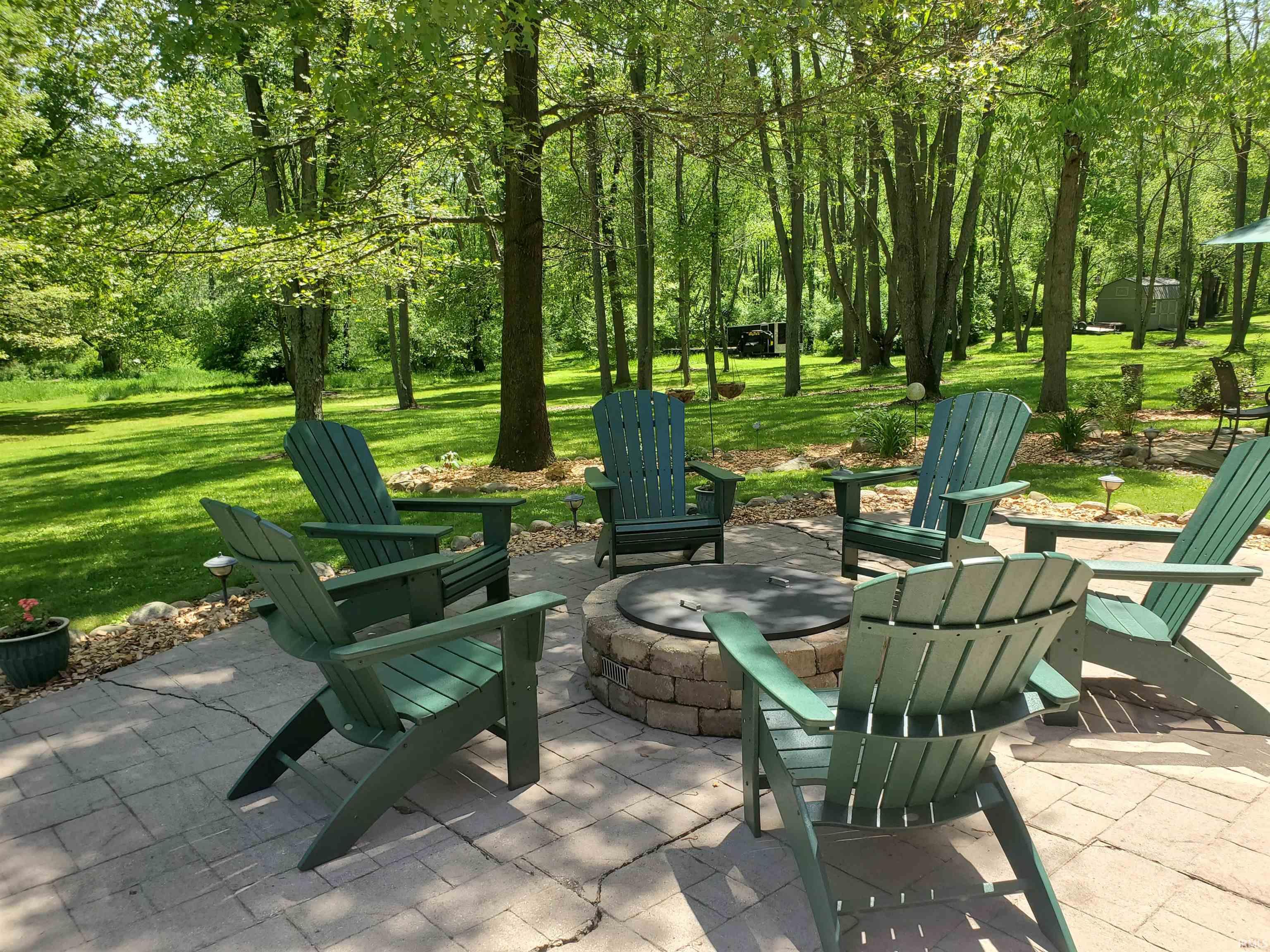 Paver patio featuring a built-in stone fire pit, surrounded by a landscaped rock border
