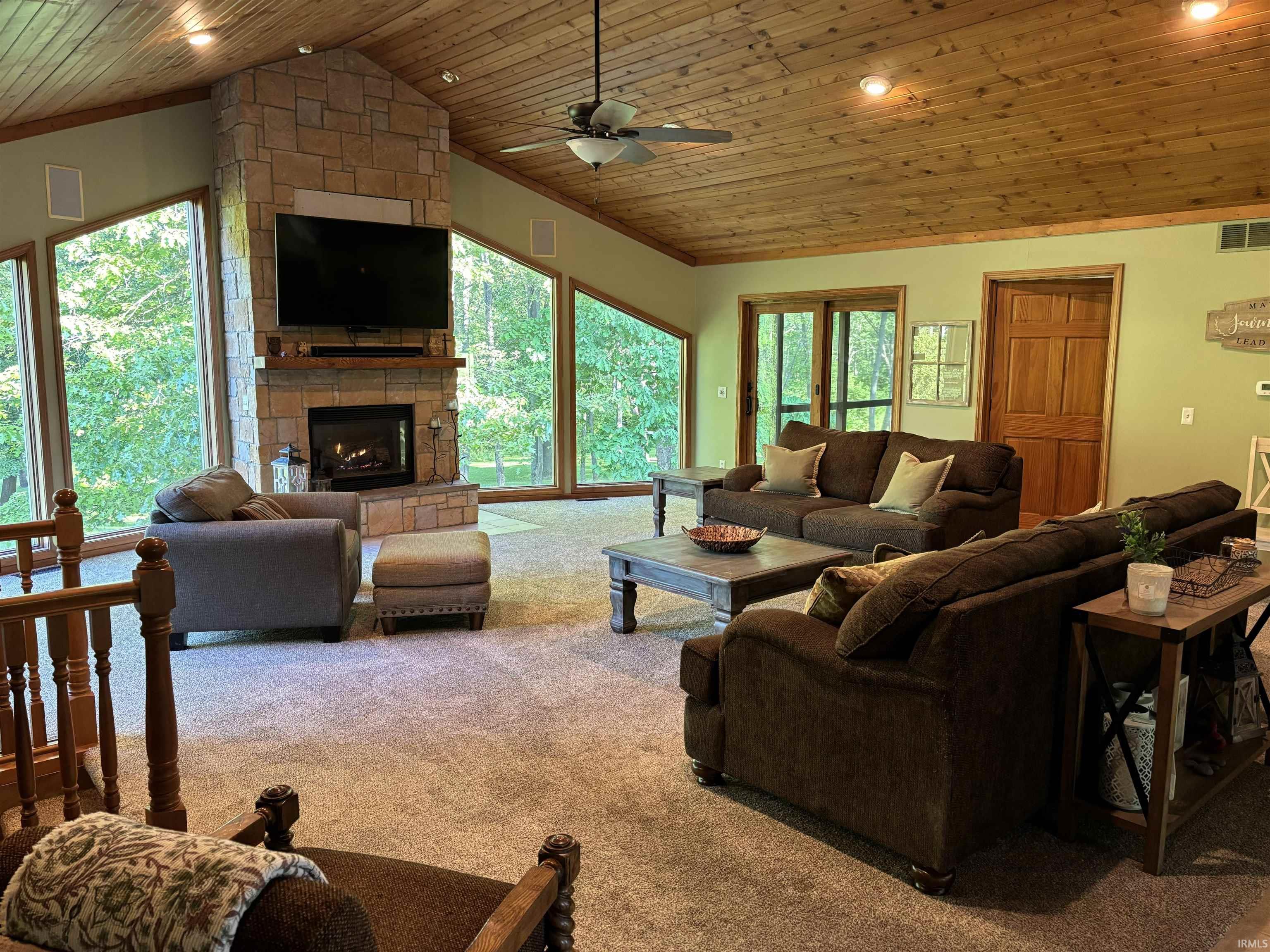 Spacious living area featuring a stone fireplace, wood-plank vaulted ceiling, extensive window placement, recessed lighting, and a ceiling fan