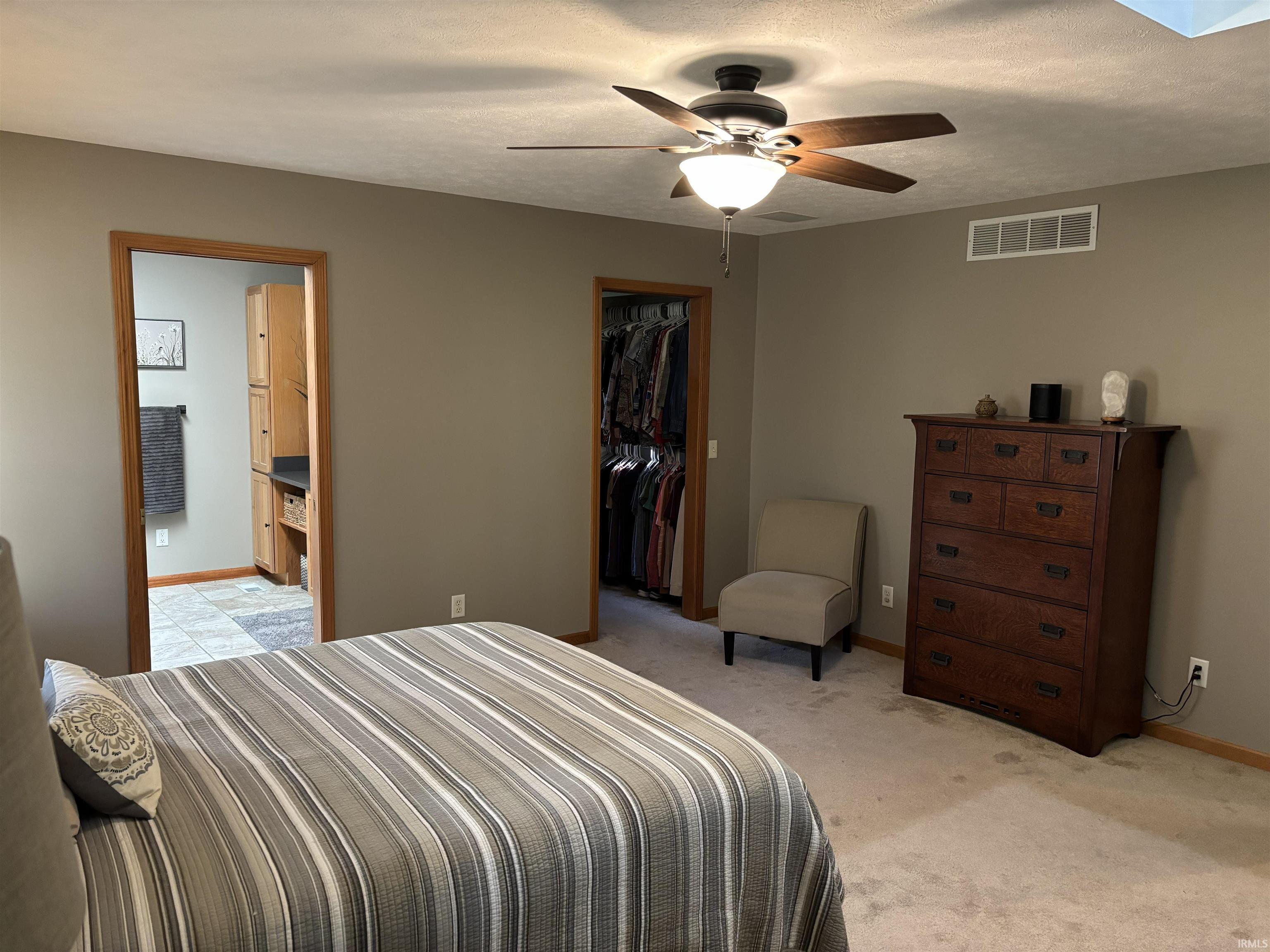 Bedroom featuring a ceiling fan with integrated lighting, neutral wall tones, and light-toned carpet flooring