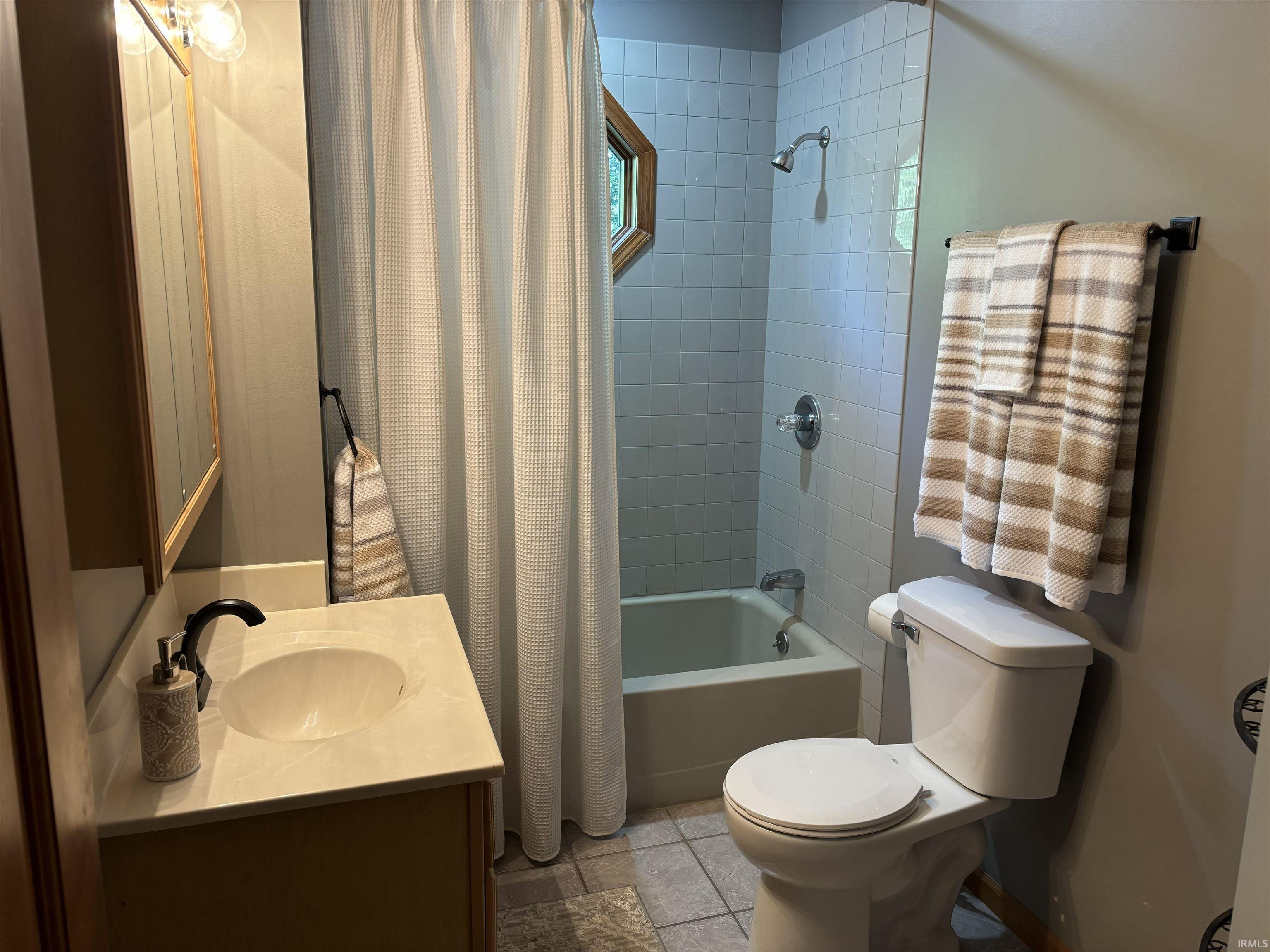 Bathroom featuring a vanity with an integrated sink, a full bathtub with tile surround, and a coordinating toilet