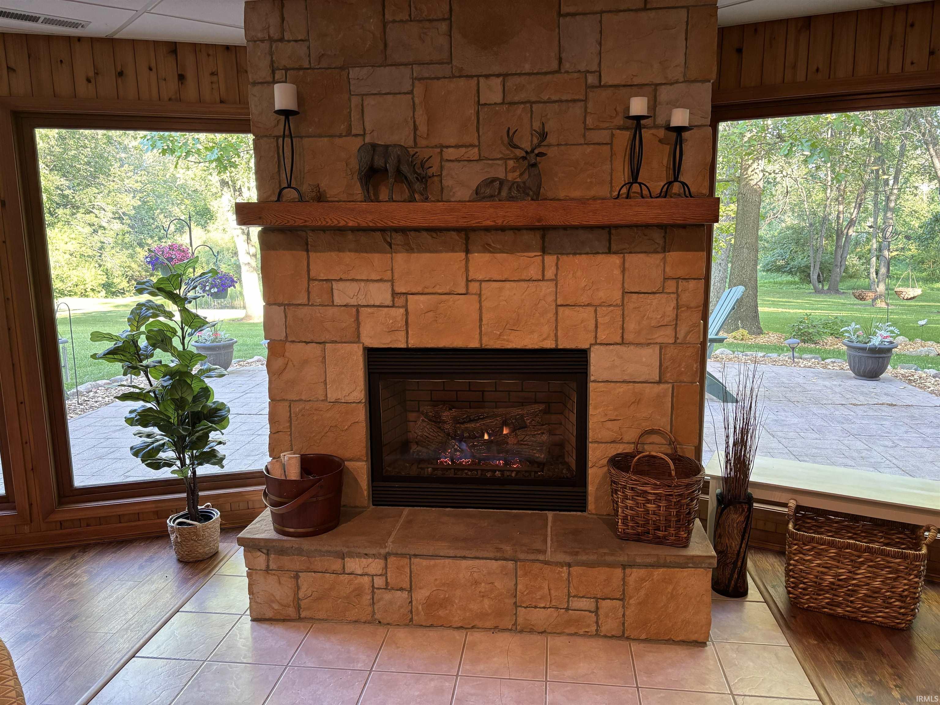 Stone fireplace with a prominent wood mantel, gas insert, and raised hearth