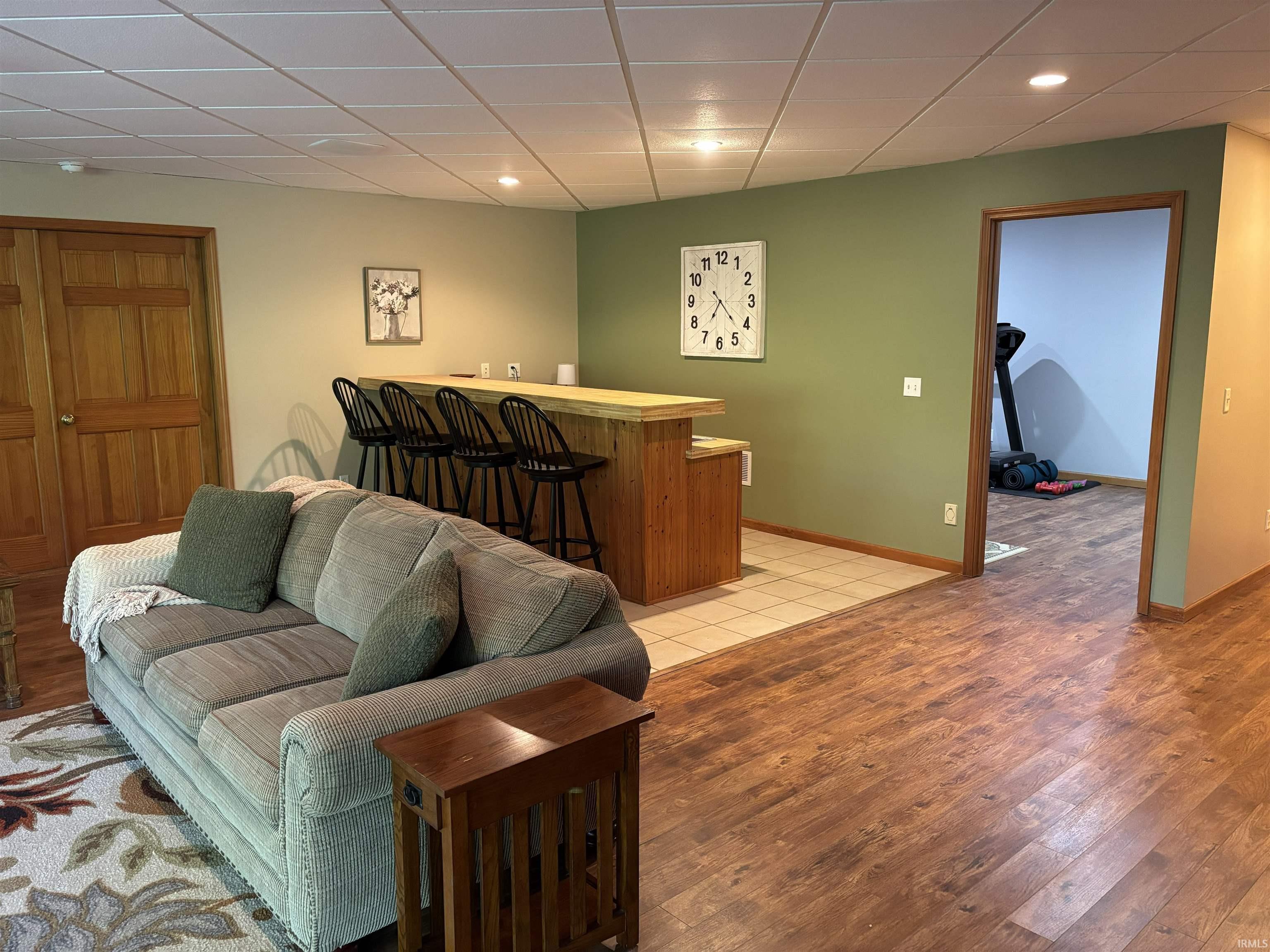 Recreational space featuring a built-in wood-finish bar with a light-toned countertop, recessed lighting, and wood-finish flooring