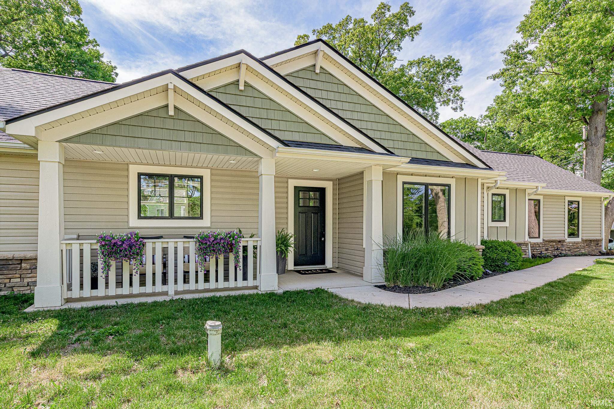 Contemporary ranch-style home featuring a covered front porch, a gabled roofline with shake siding, horizontal siding, and stone accents