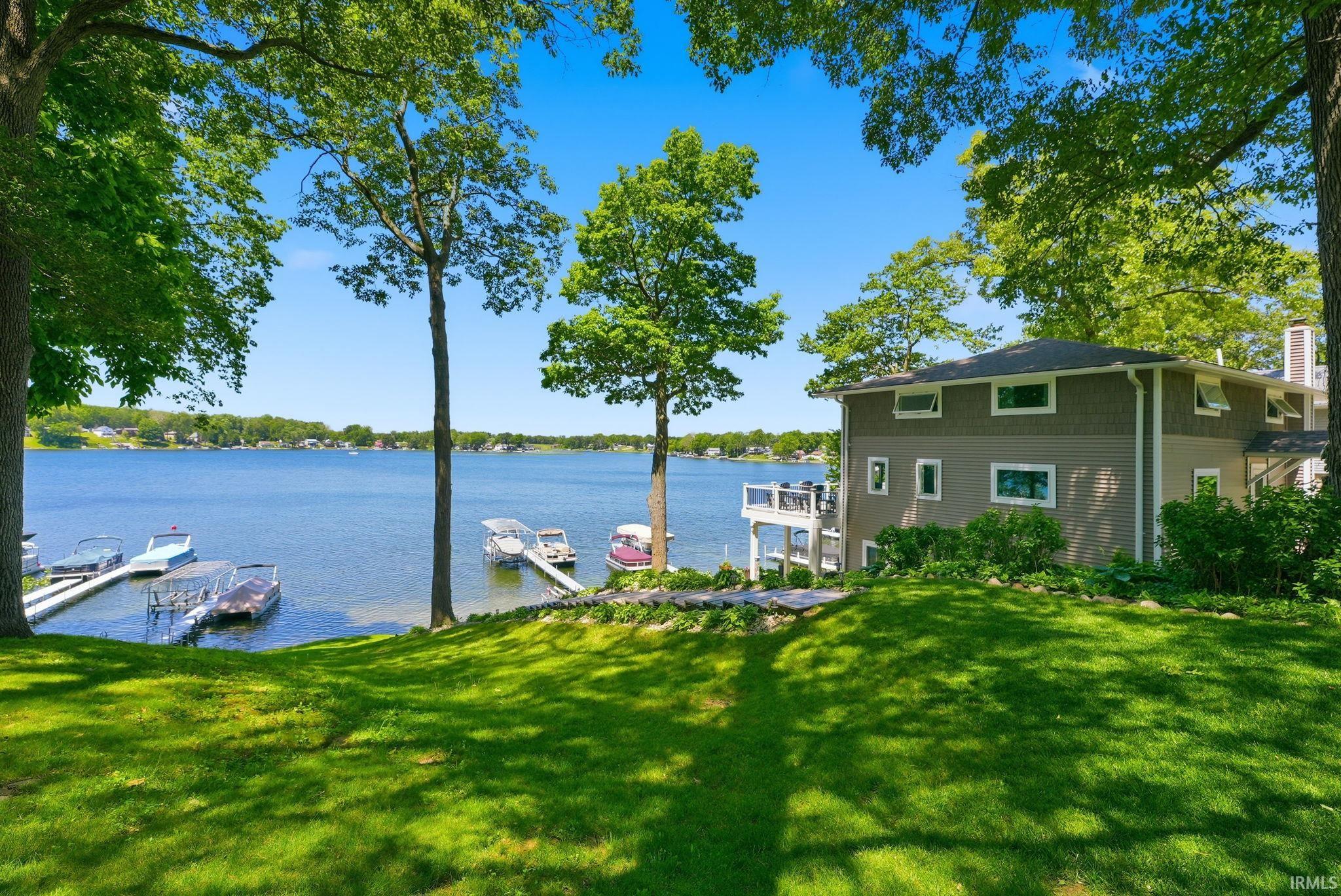 Waterside property featuring a multi-level deck, two private boat docks, and a lush green lawn