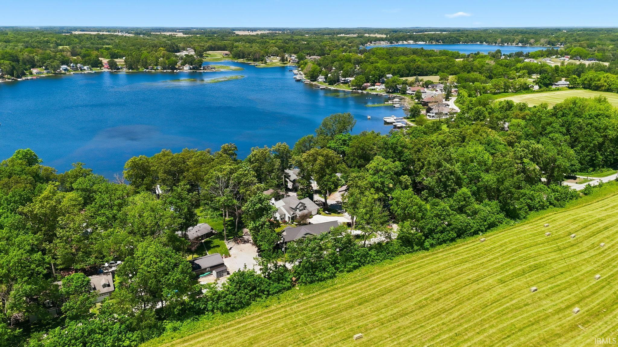 Lakefront properties with mature trees and a manicured hillside, featuring a vibrant blue lake