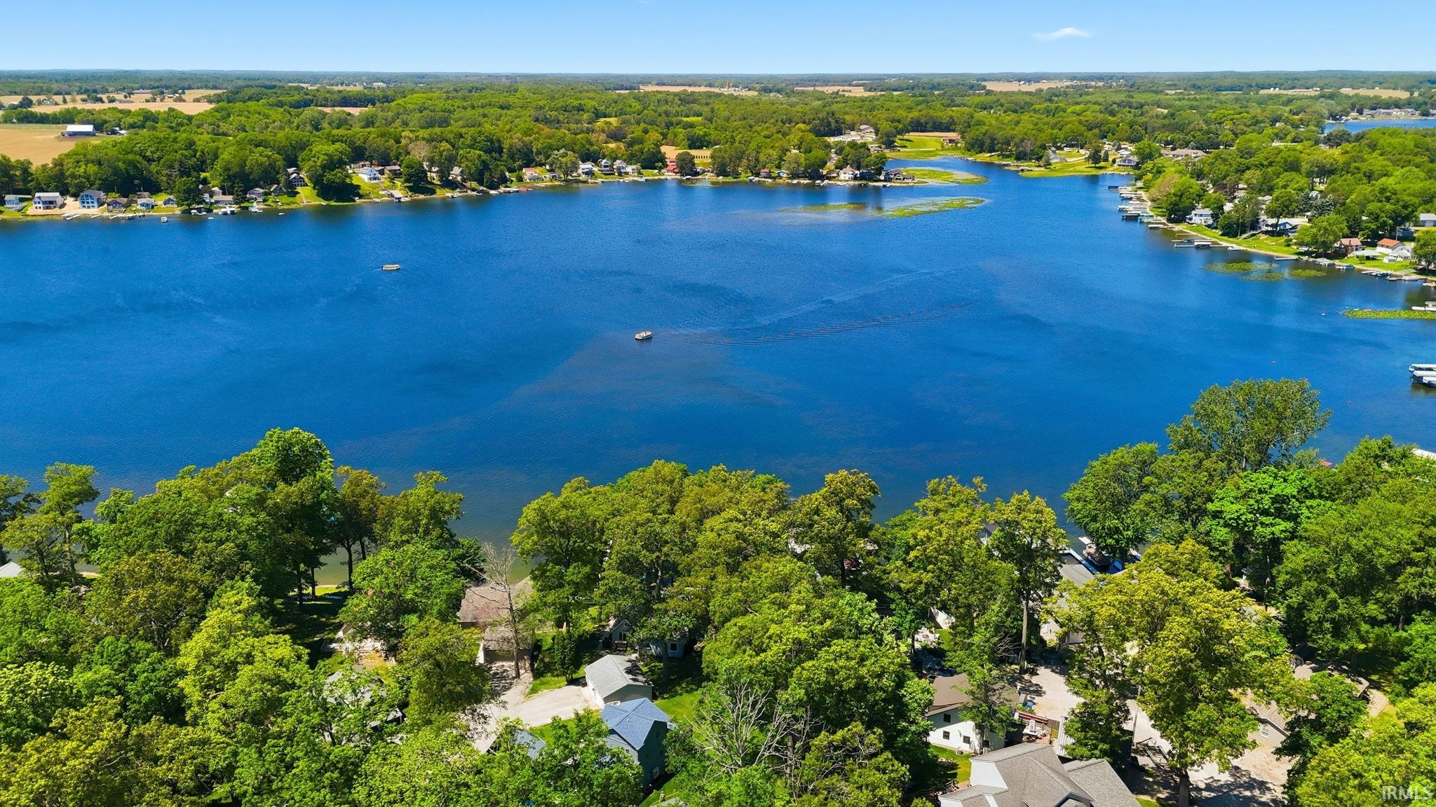 Expansive blue lake surrounded by lush green trees and residential properties