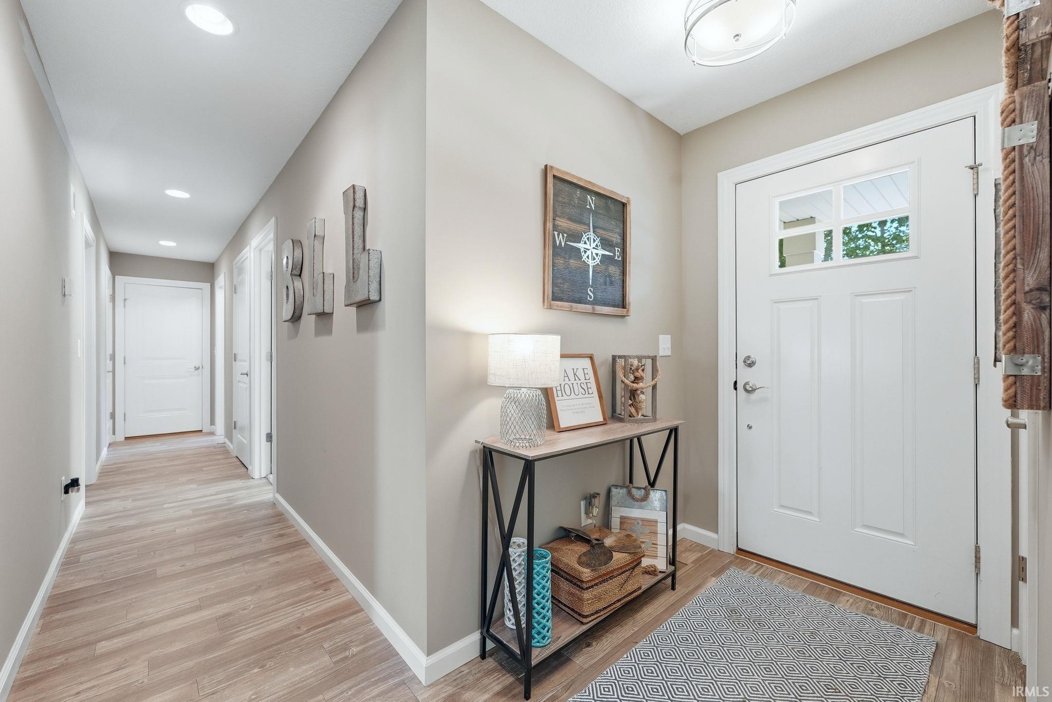 Entryway featuring a white paneled door with glass inserts, wood-finish flooring, recessed lighting, and a neutral wall color