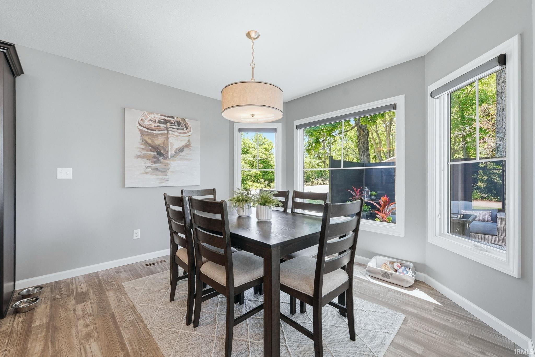 Dining area featuring wood-finish flooring, light gray wall tones, and multiple large windows