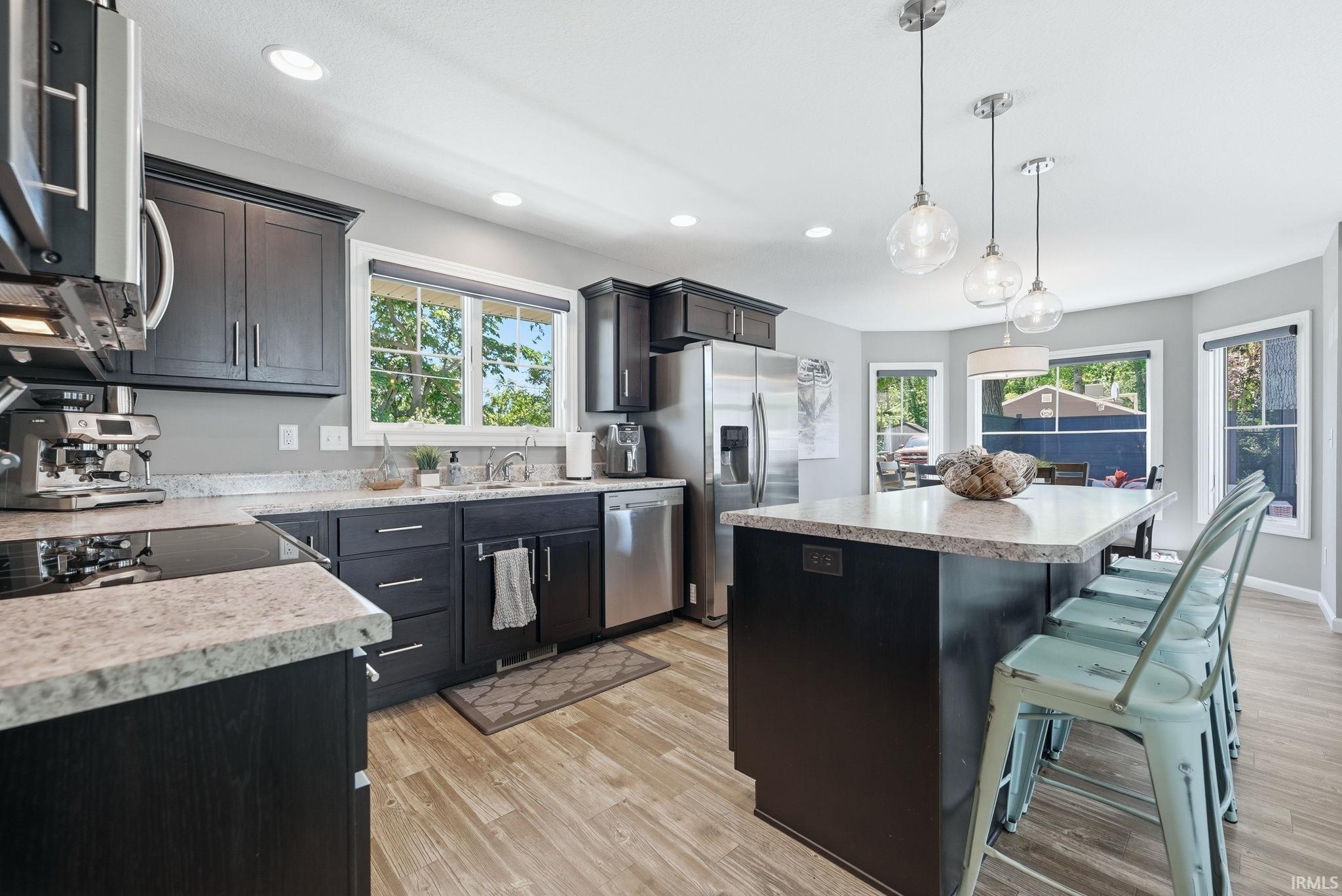 Kitchen featuring wood-finish flooring, dark cabinetry, and light-toned countertops