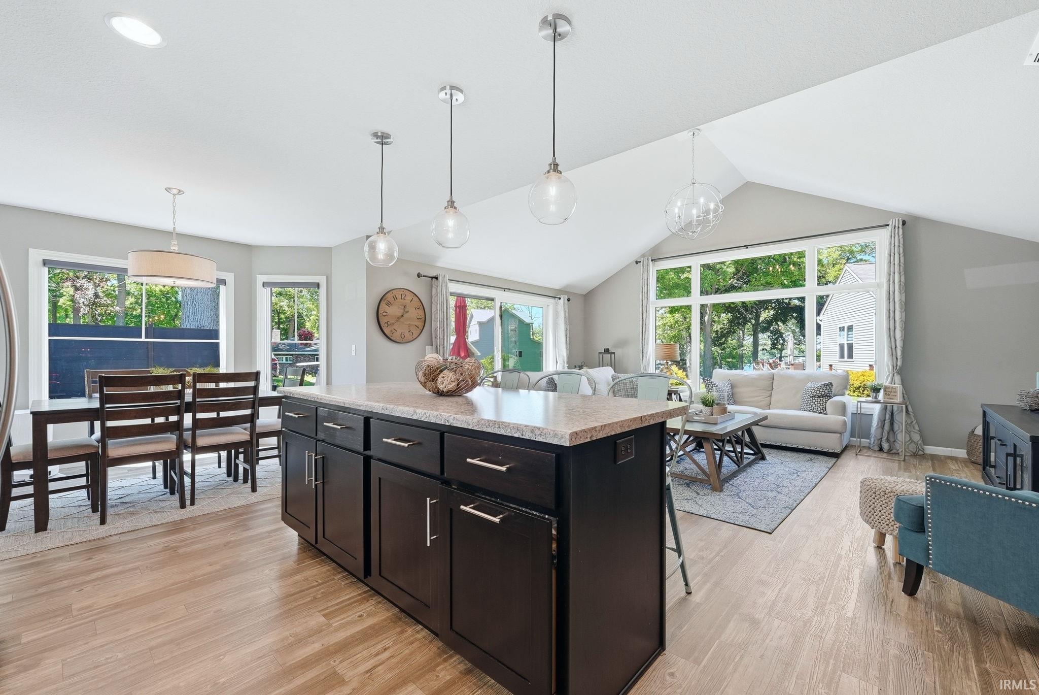 Kitchen island with dark wood cabinetry and granite-style countertop, featuring three pendant lights