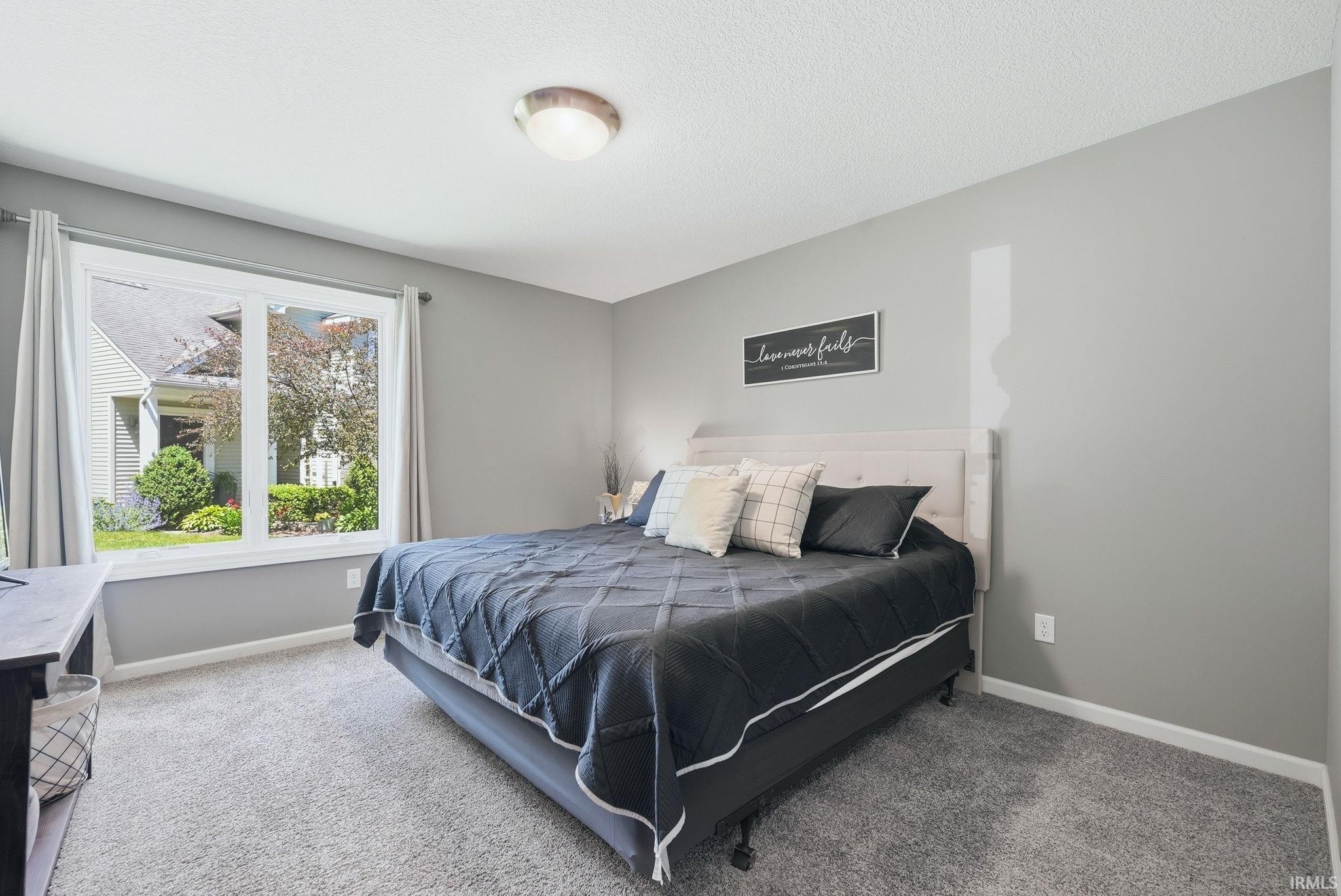 Bedroom featuring a large double window with white trim, gray walls, light gray carpet, and a flush mount ceiling light fixture