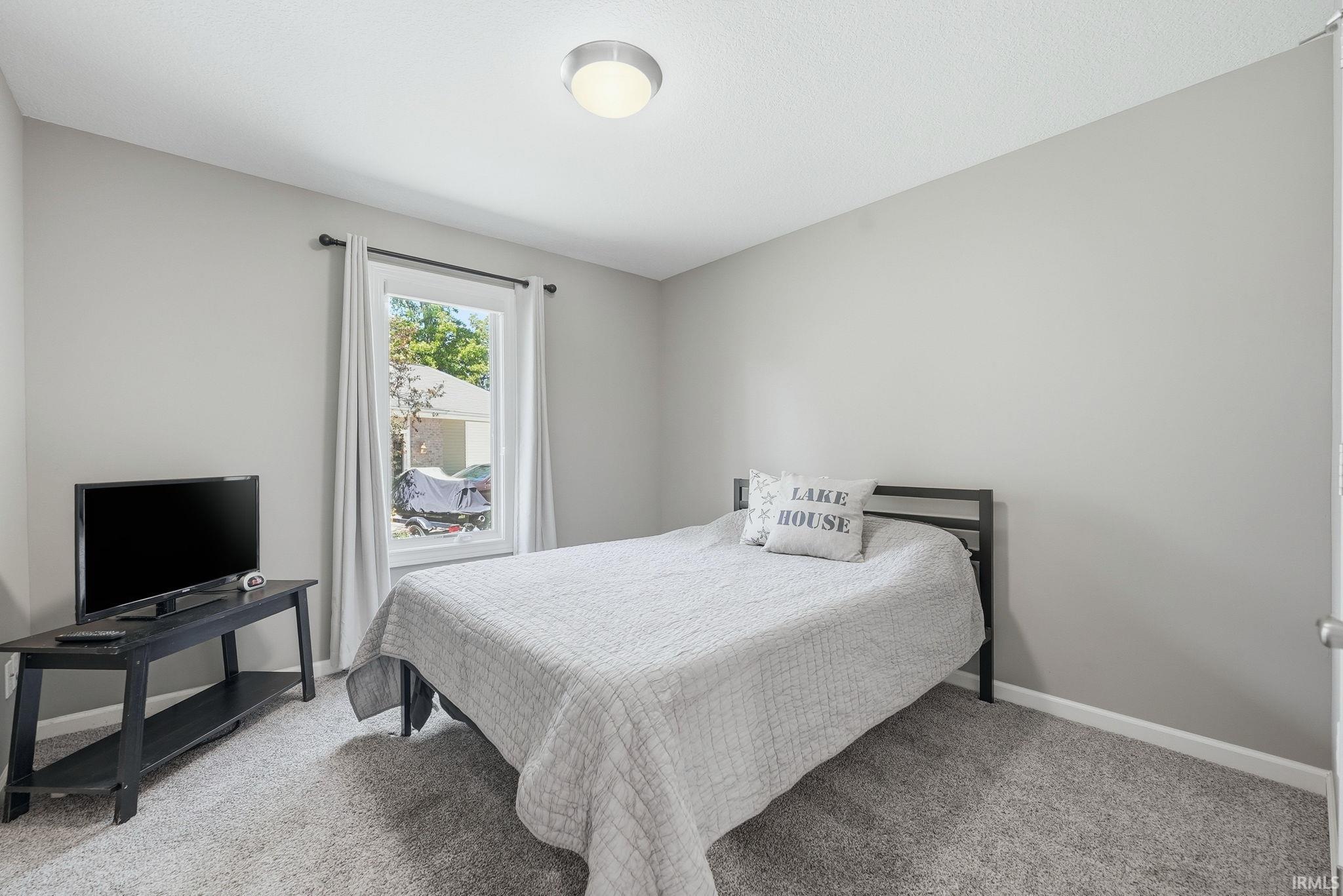 Carpeted room featuring light gray walls, a single window with white trim, and a flush-mount ceiling light