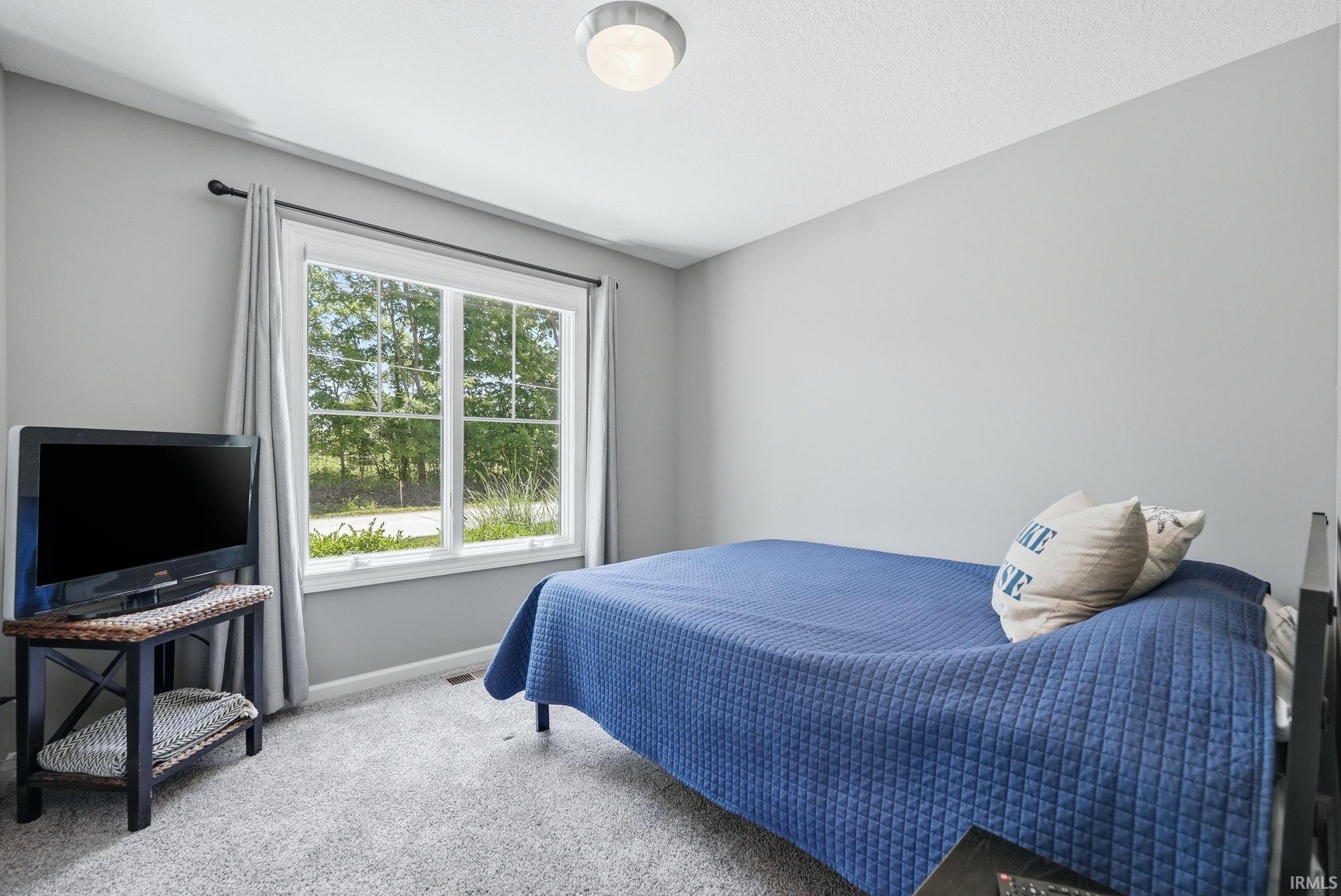 Bright interior featuring a large window, neutral wall paint, and light gray carpeting