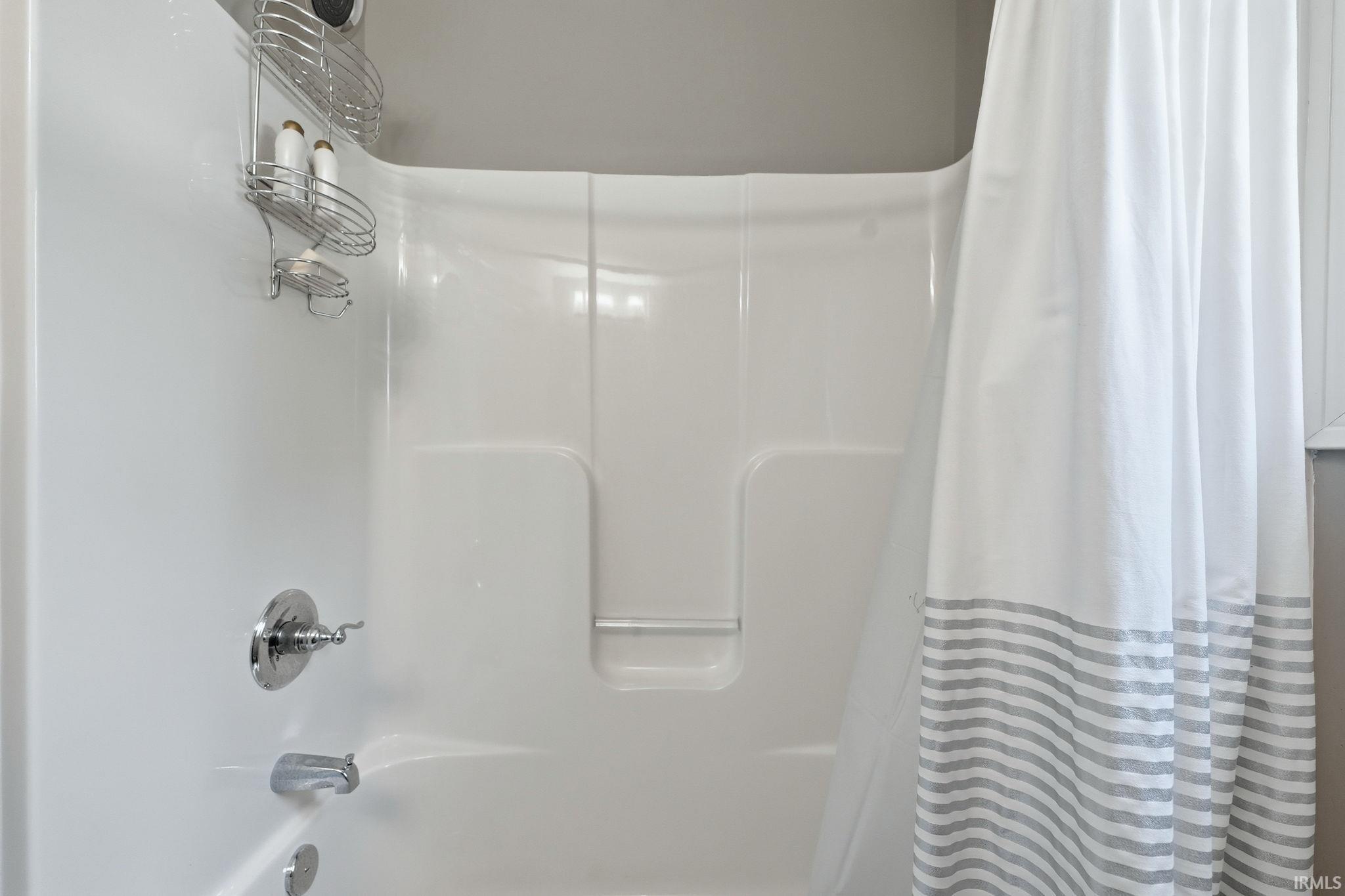 Bathtub and shower combination featuring a polished chrome faucet and shower head