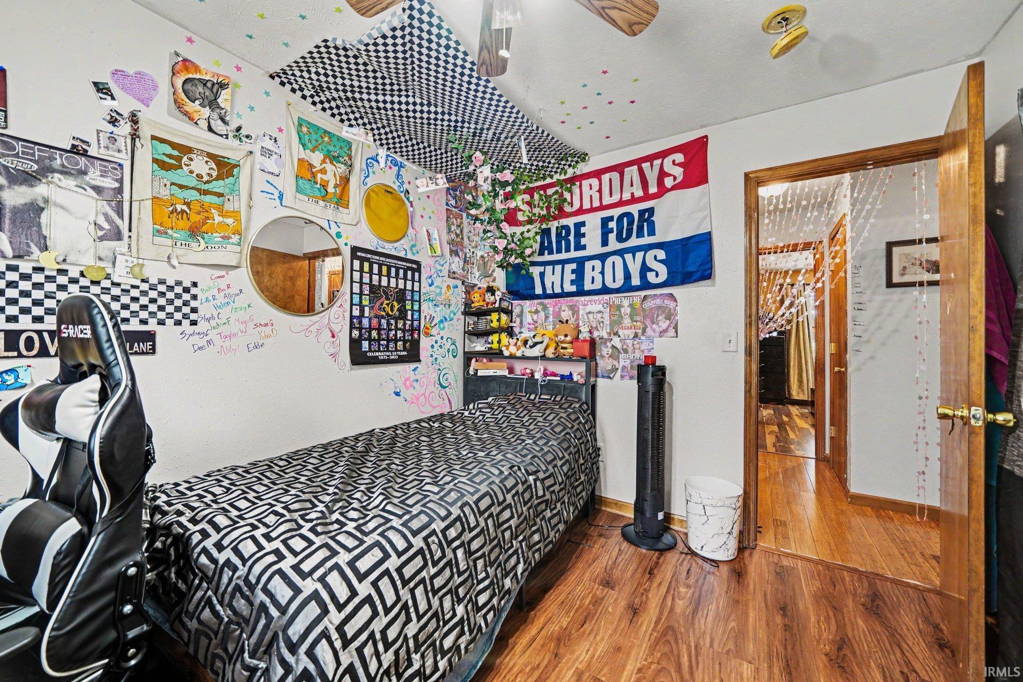 Room featuring wood-finish flooring, a ceiling fan, and a wood-paneled door frame
